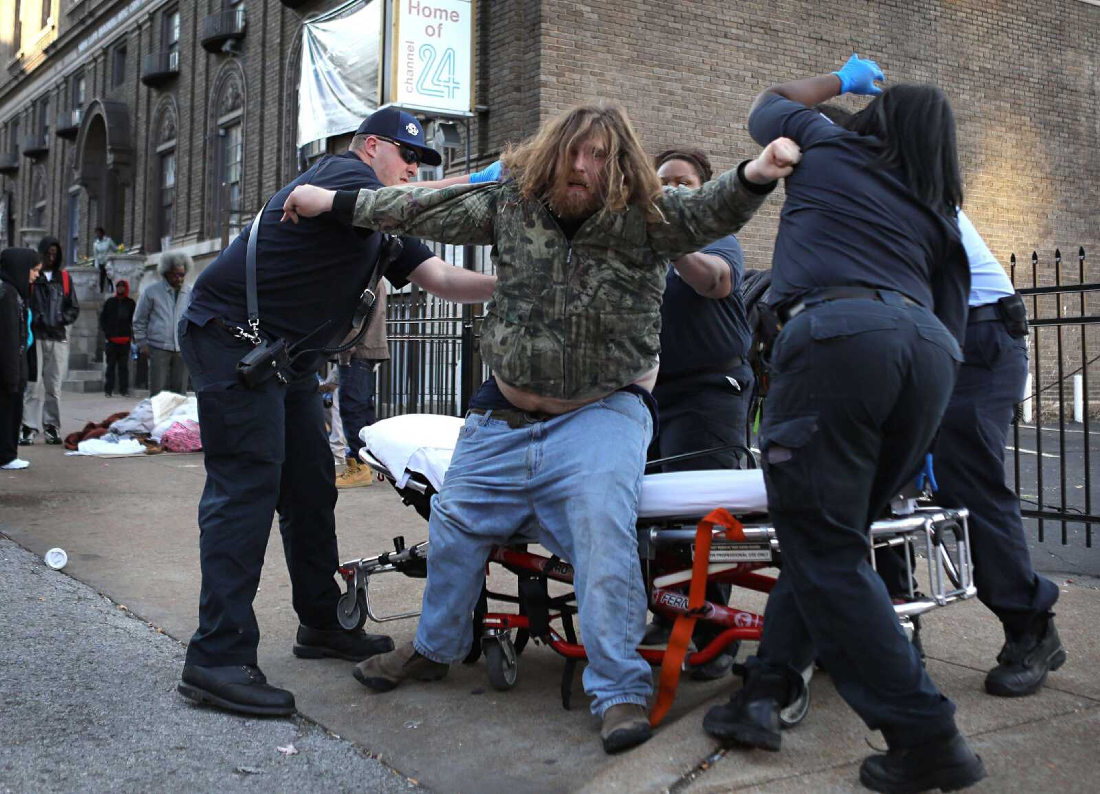 Firefighters and medics try to help a man onto a stretcher after he was found semiconscious on the ground Nov. 11 in St. Louis. The man is believed to be one of several hundred who have become ill recently in St. Louis after possibly using the latest version of synthetic marijuana, a man-made hallucinogen experts say is far more dangerous and unpredictable than the real thing.