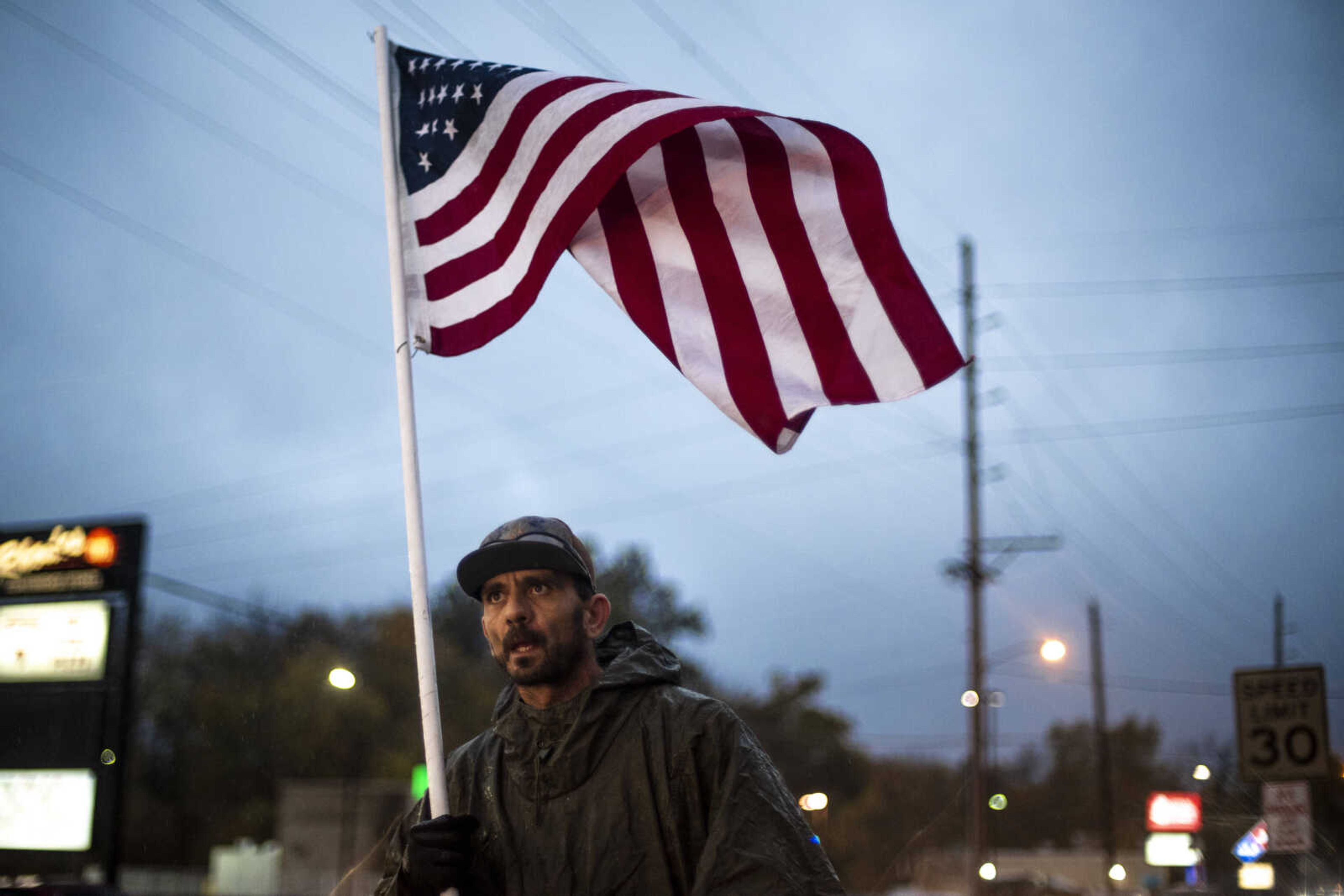 Eric Patterson, of Farmington, MO, carries an American flag through the rain down Sprigg St. Monday, Nov. 5, 2018, in Cape Girardeau.