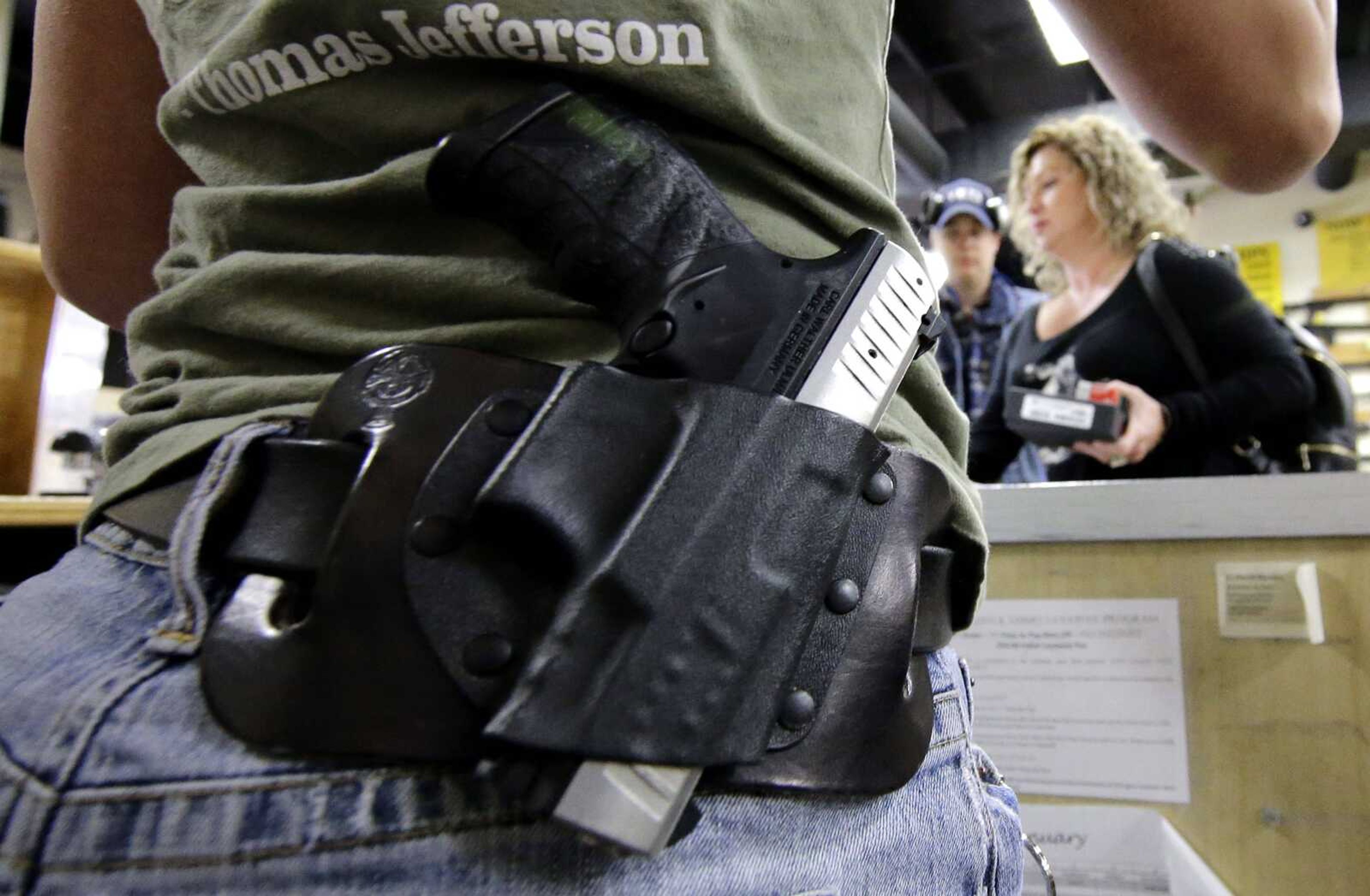 Kayla Brown, left, wears her gun on her hip while working at the Spring Guns and Amo store Monday in Spring, Texas. (David J. Phillip ~ Associated pRess)