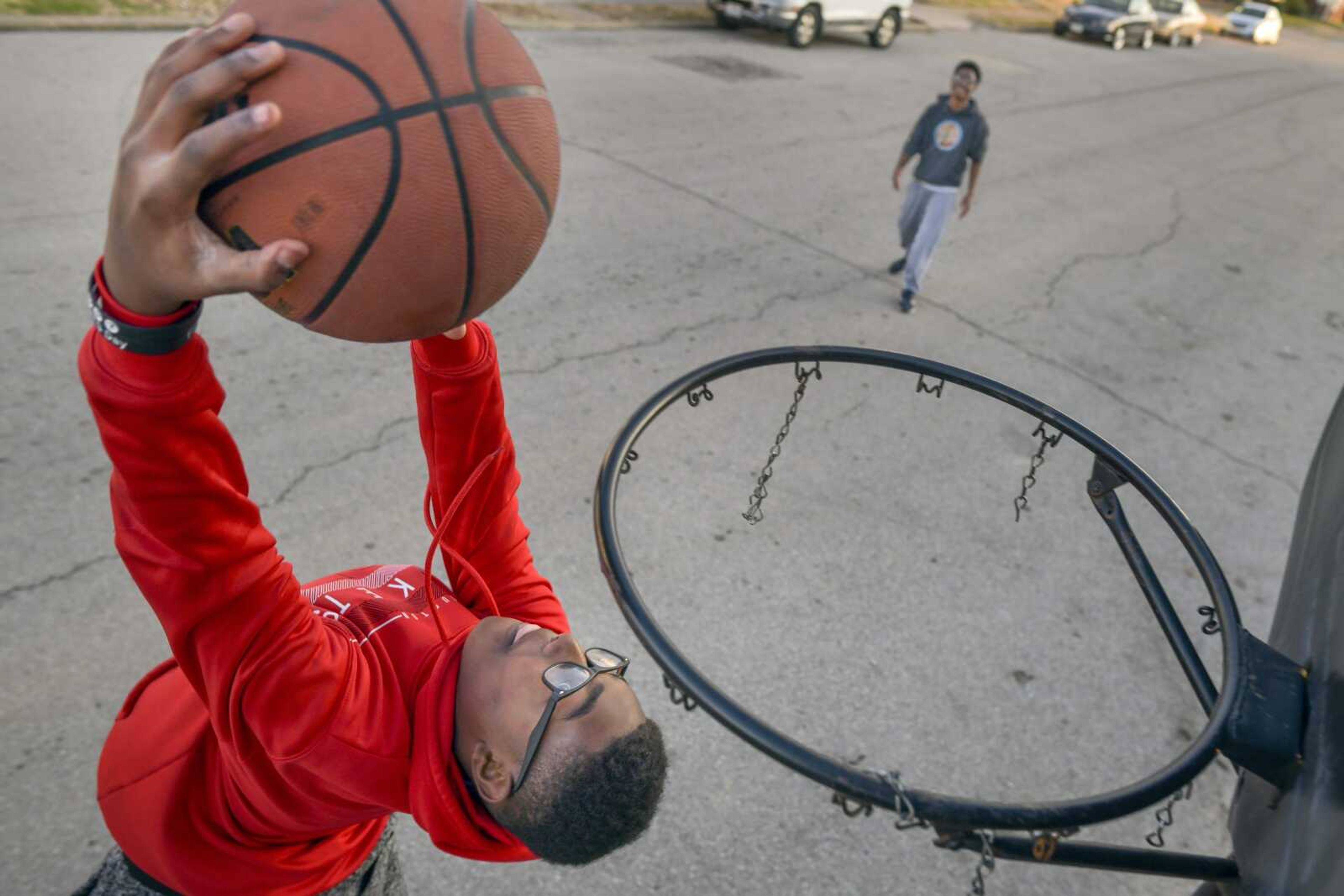 Jonathan Harris, 13, throws down a reverse dunk as his older brother, Zacheriah, looks on while playing basketball Jan. 14 on South Ellis Street in Cape Girardeau. "I had to teach myself [how to play basketball]," Zacheriah said. "And then I had to teach him (Jonathan.)" "That's why I'm so good," Jonathan added. "Better than him!"