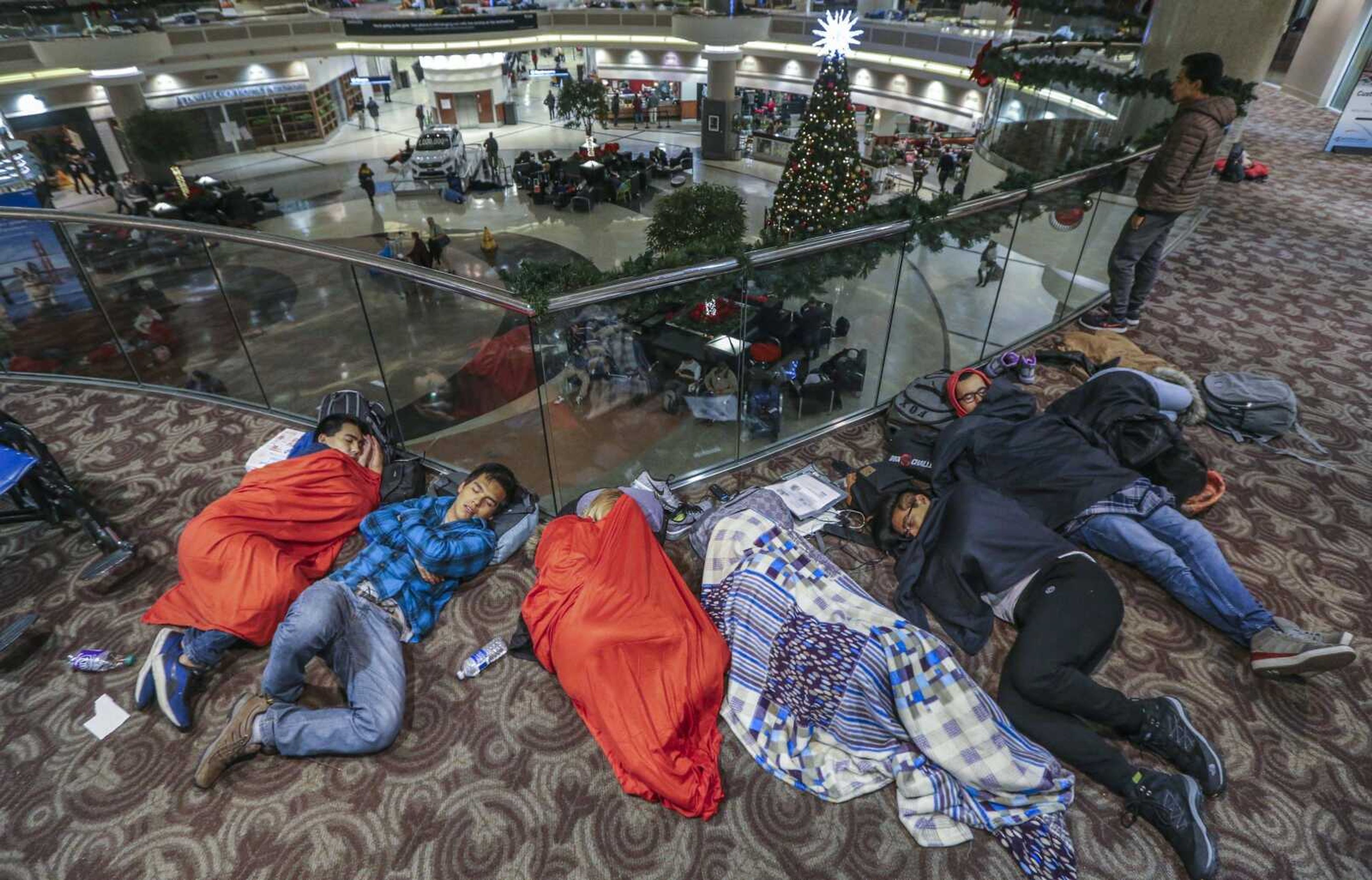 Travelers sleep in the atrium Monday at Hartsfield-Jackson International Airport in Atlanta, the day after a massive power outage brought operations to a halt. Power was restored at the world's busiest airport after a massive outage Sunday afternoon that left planes and passengers stranded for hours, forced airlines to cancel more than 1,100 flights and created a logistical nightmare during the already-busy holiday travel season.