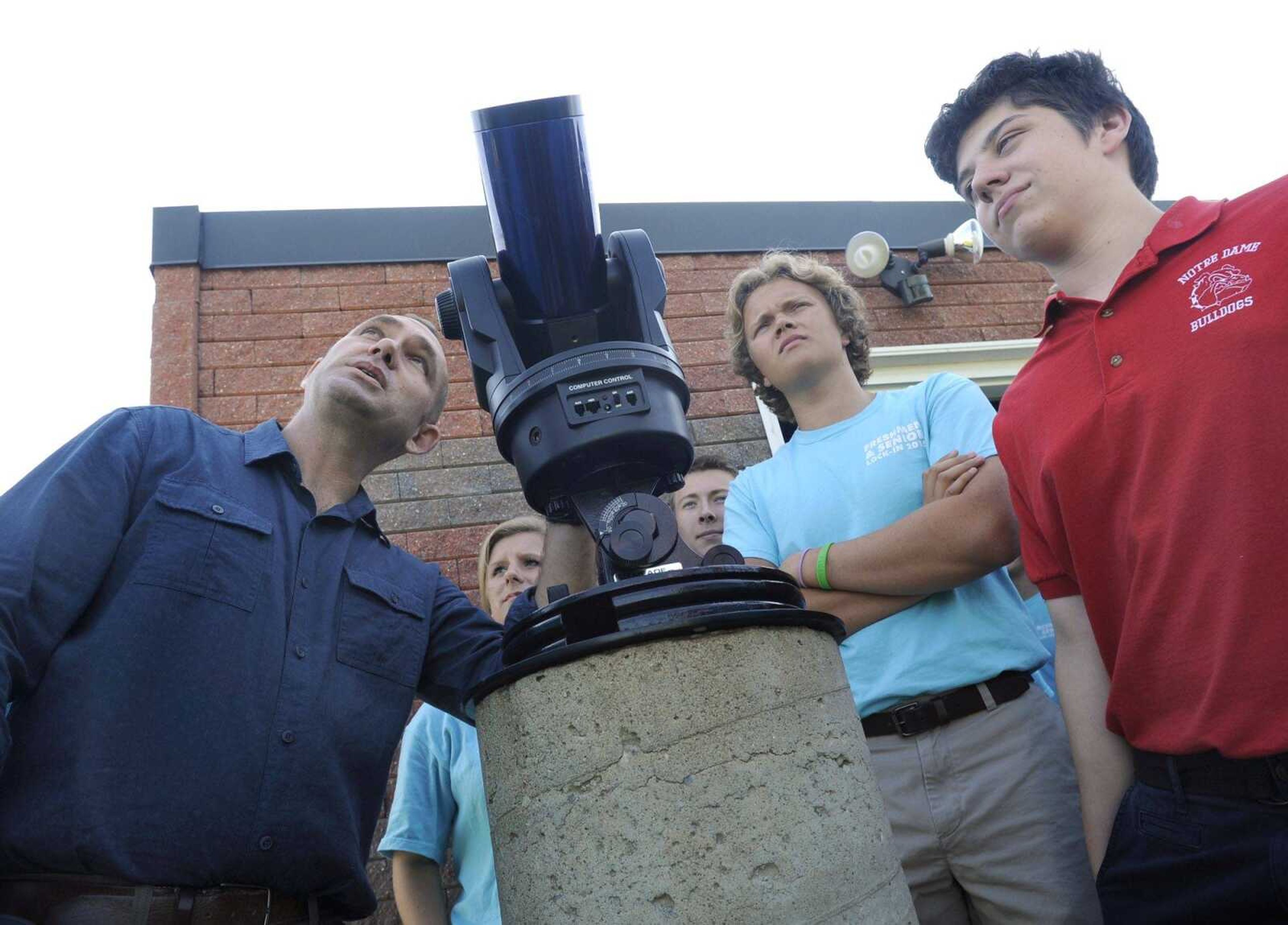 Science teacher Jerry Landewe, left, shows a tracking telescope to his senior astronomy class Monday with Ryan Eftink, right, and Evan Unterreiner at Notre Dame Regional High School. (Fred Lynch)