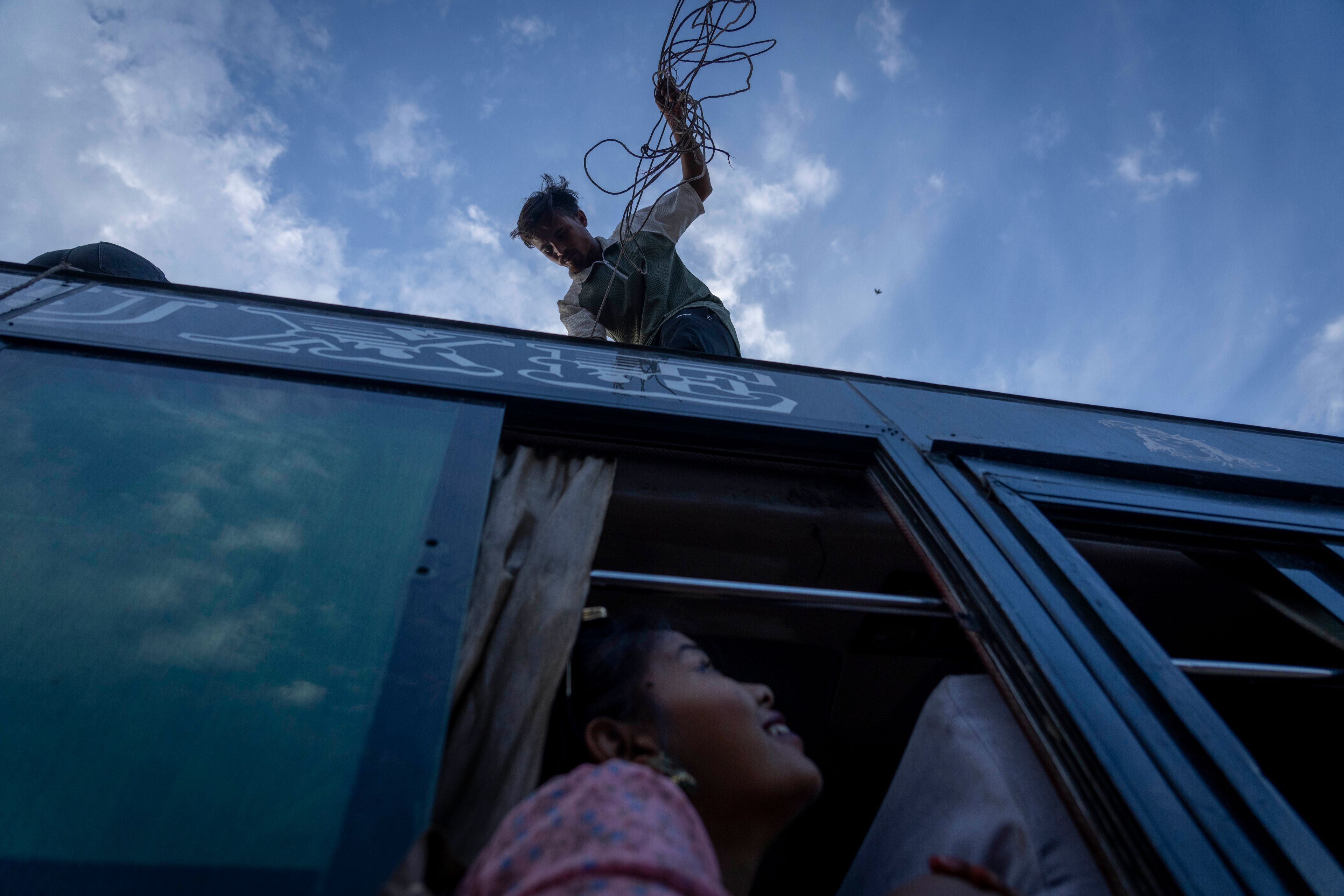 A bus staffer loads passengers' belongings at a Kathmandu station before departing for villages to celebrate the Dashain festival, in Kathmandu, Nepal, Thursday, Oct. 10, 2024. Dashain, the most important religious festival of Nepal's Hindus, commemorates the victory of the gods over demons. (AP Photo/Niranjan Shrestha)