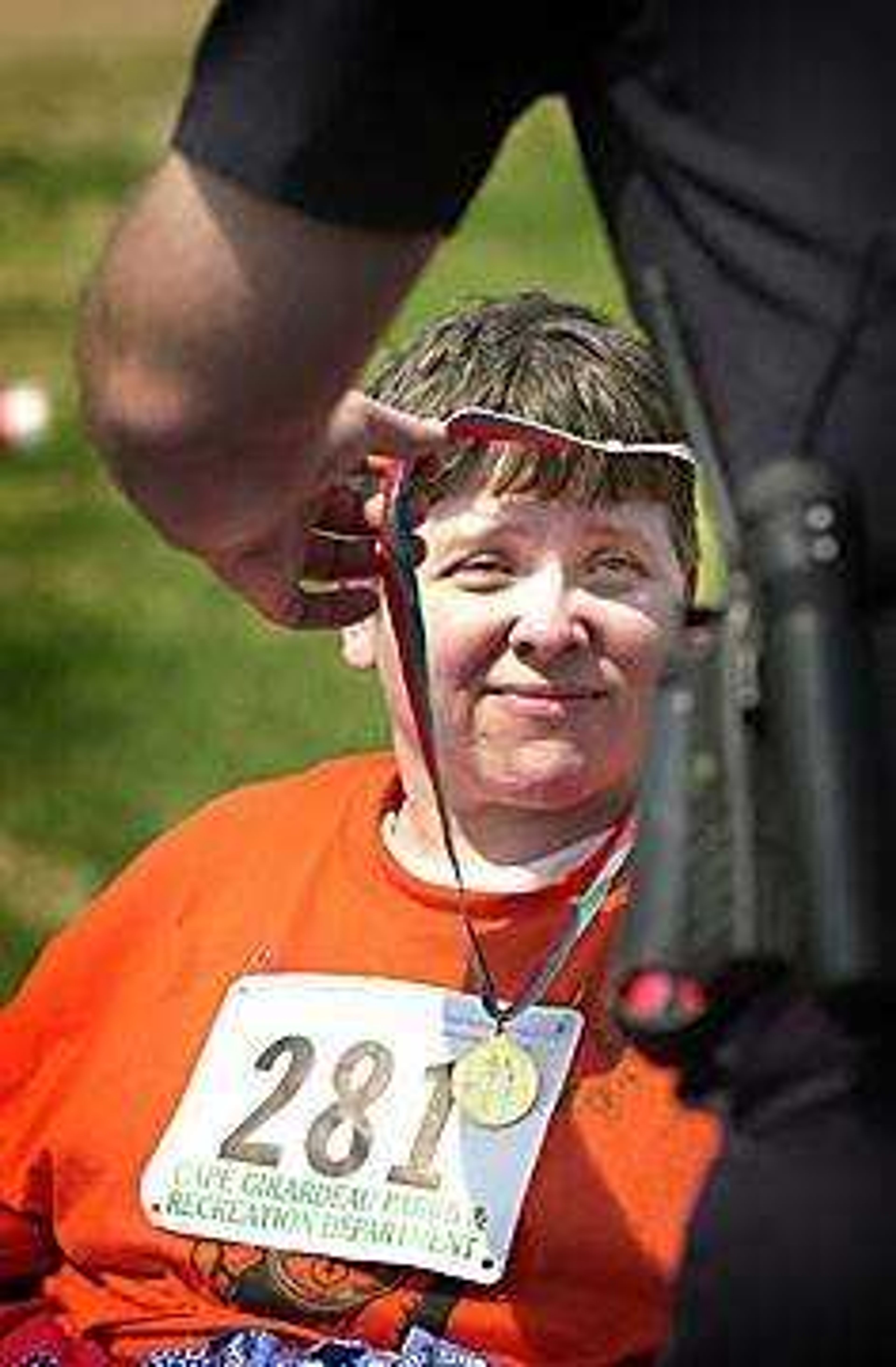 Cindy Fowler of Marble Hill received a gold medal in the Tee Ball Throwing competition from Officer Brown of the Cape Girardeau police department