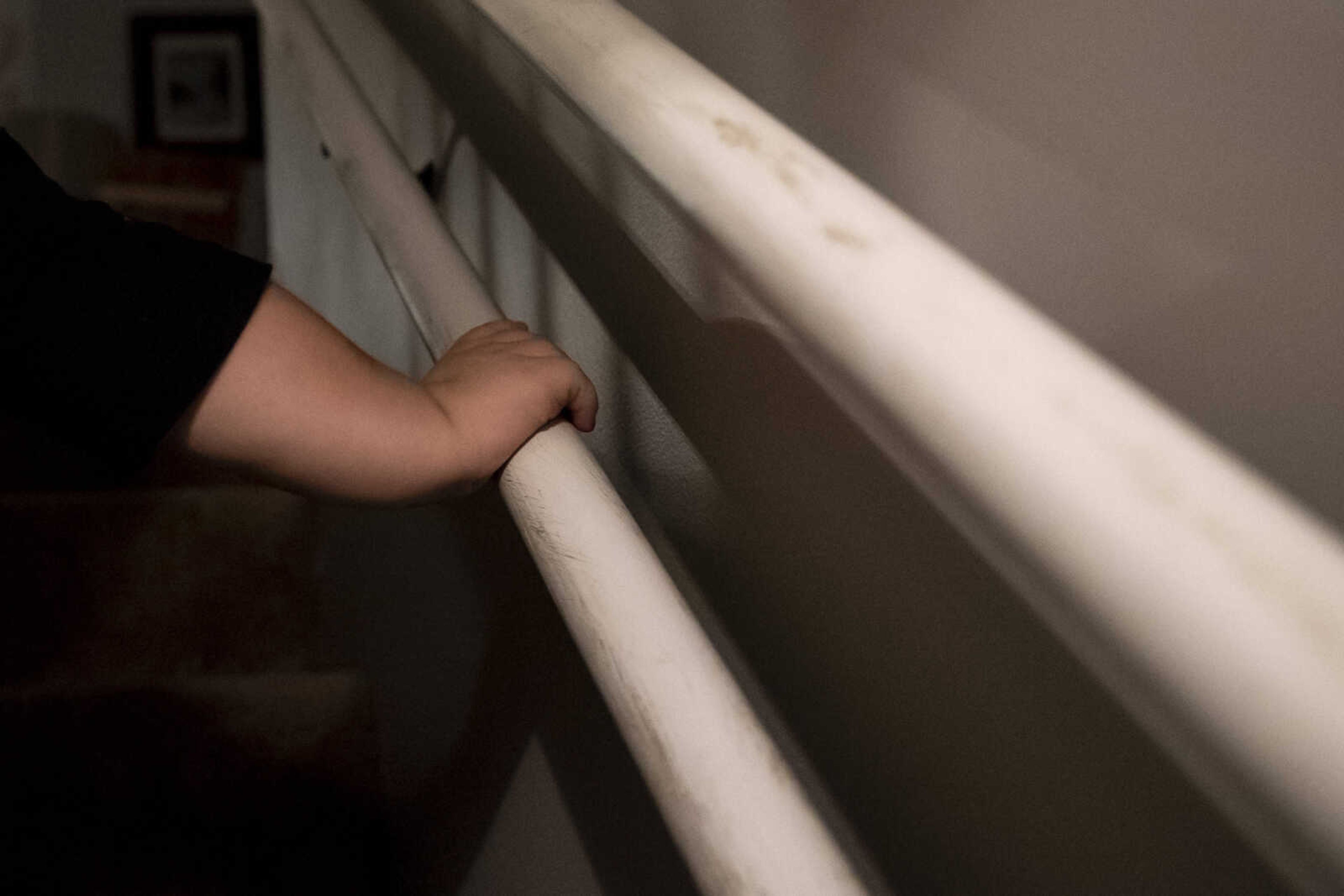 Izaac Pursley uses the handrail installed specifically for his height in his family's basement stairway Oct. 1, 2018, in Jackson.