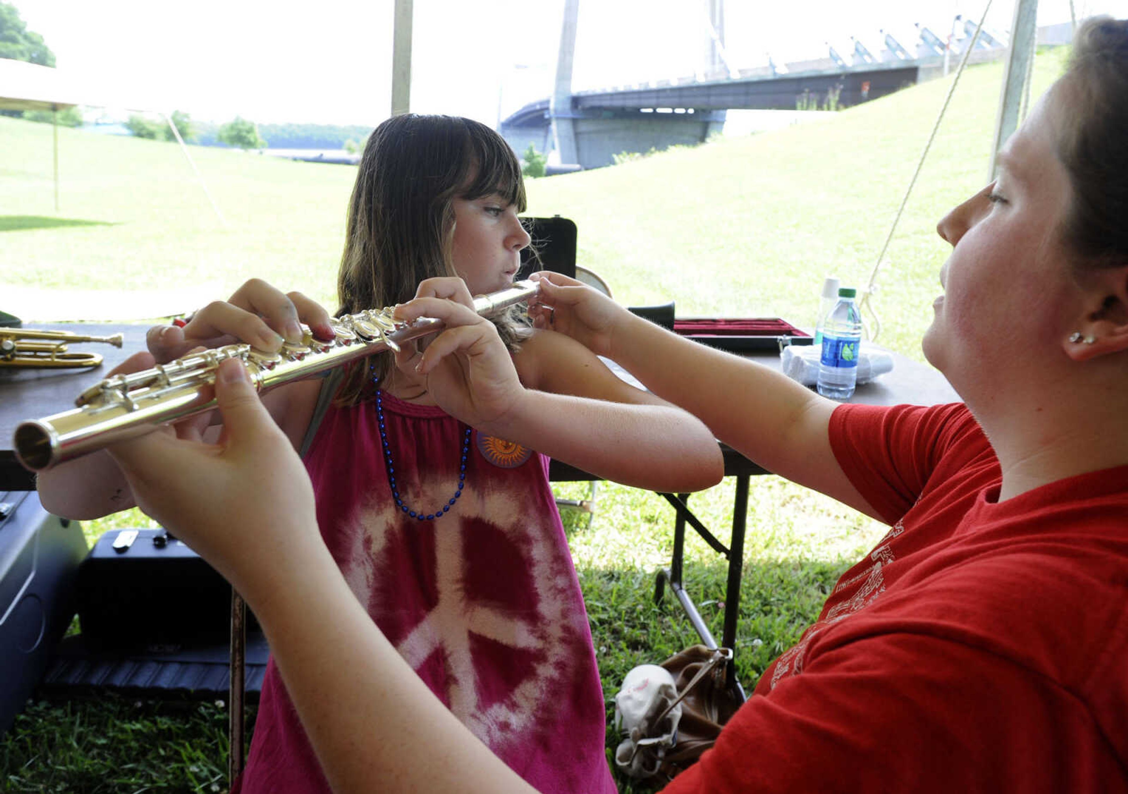 Katherine Ebersohl tries playing a flute with help from Lauren Murray in the art tent Saturday, June 21, 2014 at the River Campus Summer Arts Festival in Cape Girardeau.