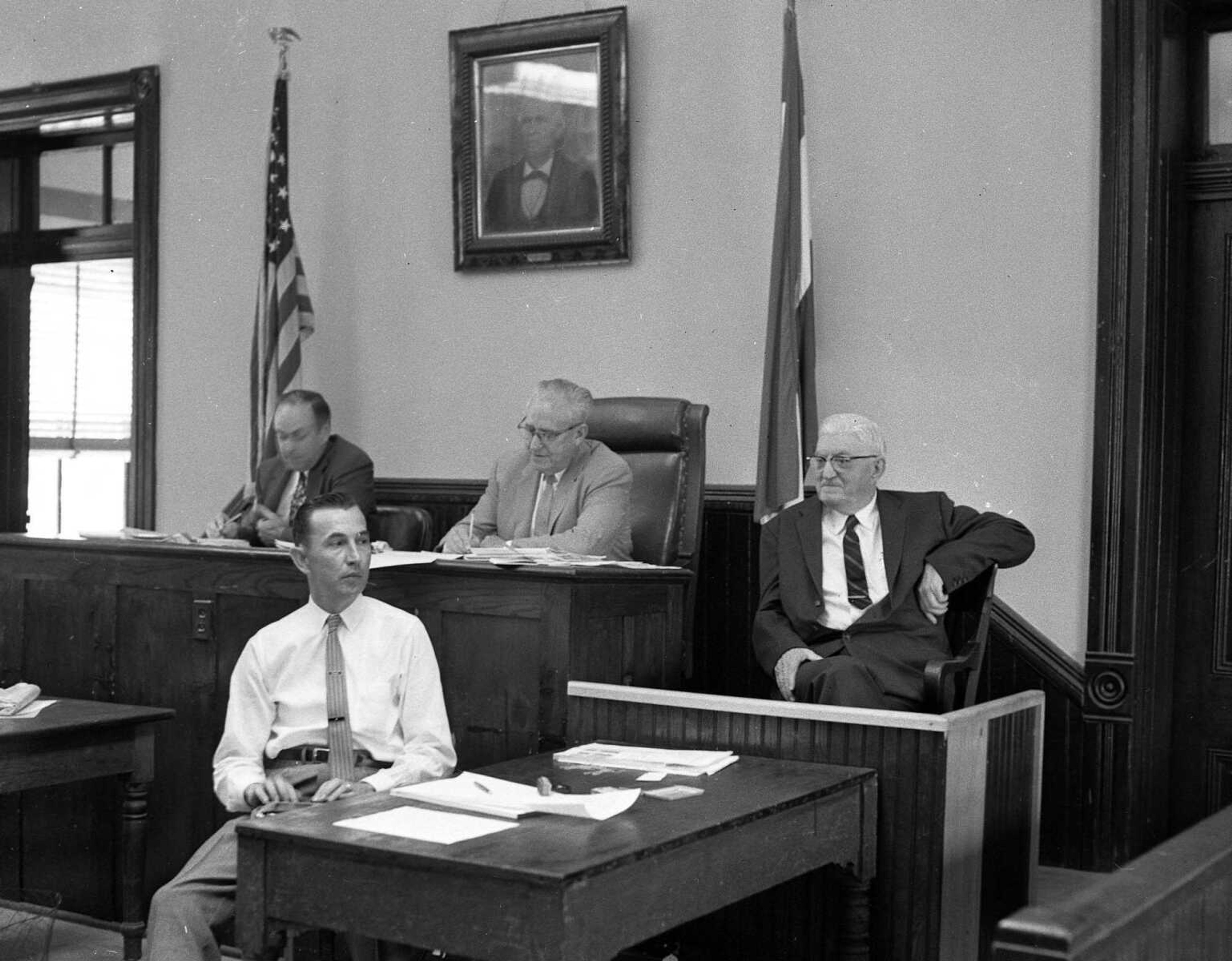 In june 1958, a hearing was held in Common Pleas Courthouse on the Frisco Railroad's proposal to abandon night passenger train service. The two men on the bench are Public Service Commissioners W.W. Barton and E.L. McClintock. The other two men are unidentified.