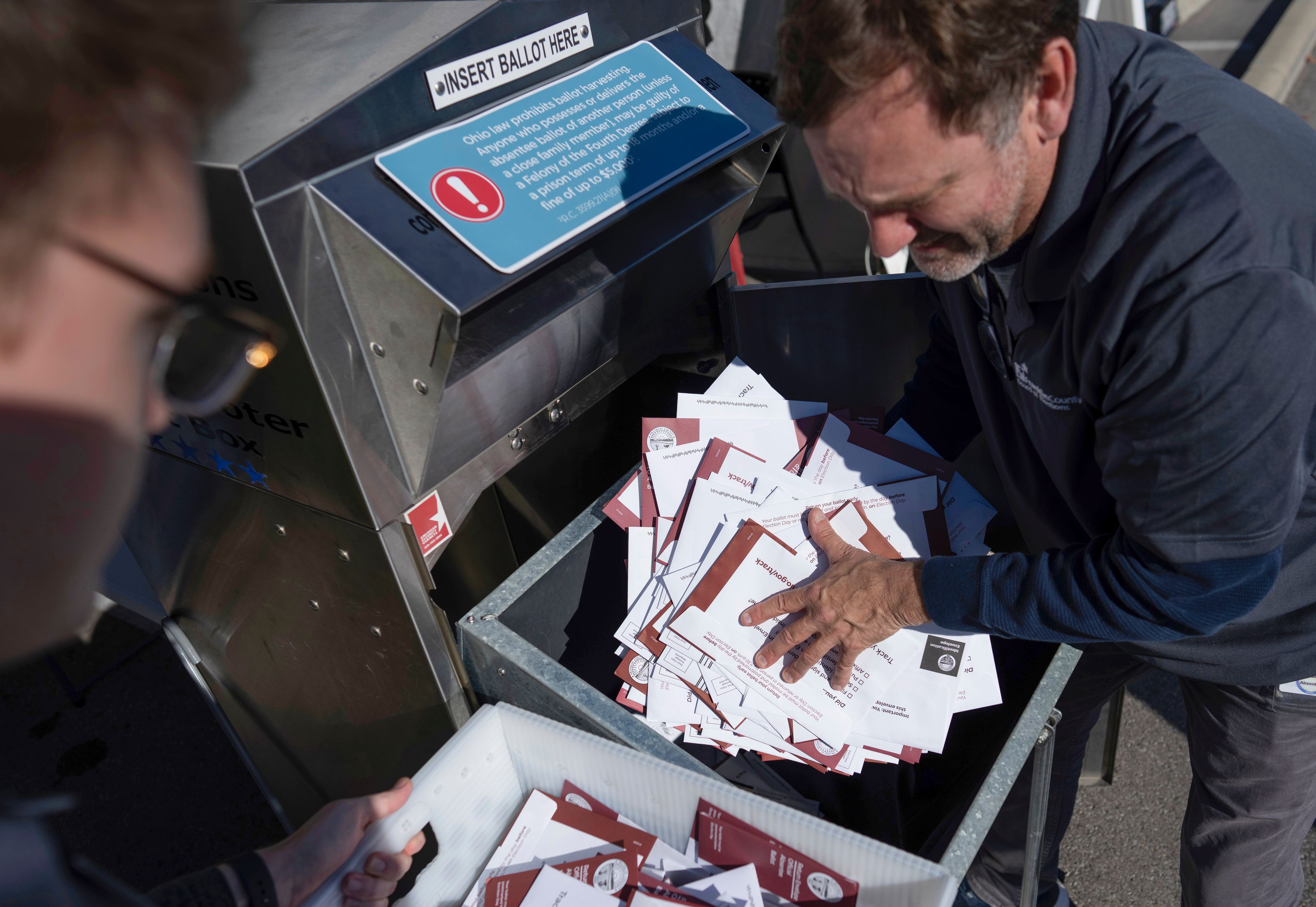 FILE - Seth Golding, right, and Braydon Galliers, left, a bipartisan team of ballot fulfillment coordinators, empty an absentee voter drop-off ballot box on Election Day outside of the Franklin County Board of Elections in Columbus, Ohio, Tuesday, Nov. 7, 2023. (AP Photo/Carolyn Kaster, File)