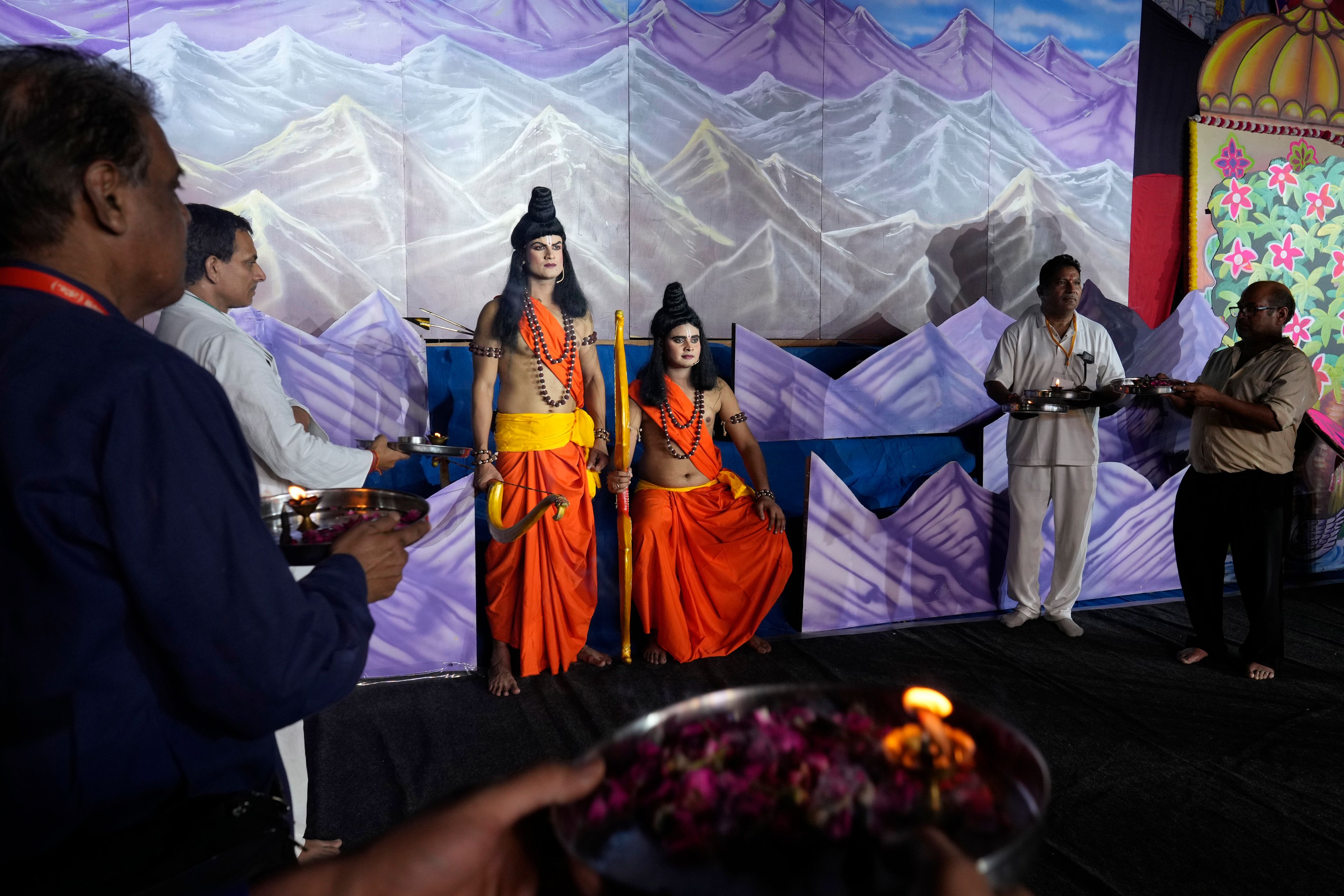 Two actors who played Hindu god Rama, sitting, and his brother Laxman, standing next to him in the center, wait on the stage at the end of the third day of Ramleela, a dramatic folk re-enactment of the life of Rama according to the ancient Hindu epic Ramayana, as event organizers and donors pray to them, in New Delhi, India, Wednesday, Oct. 9, 2024. (AP Photo/Manish Swarup)