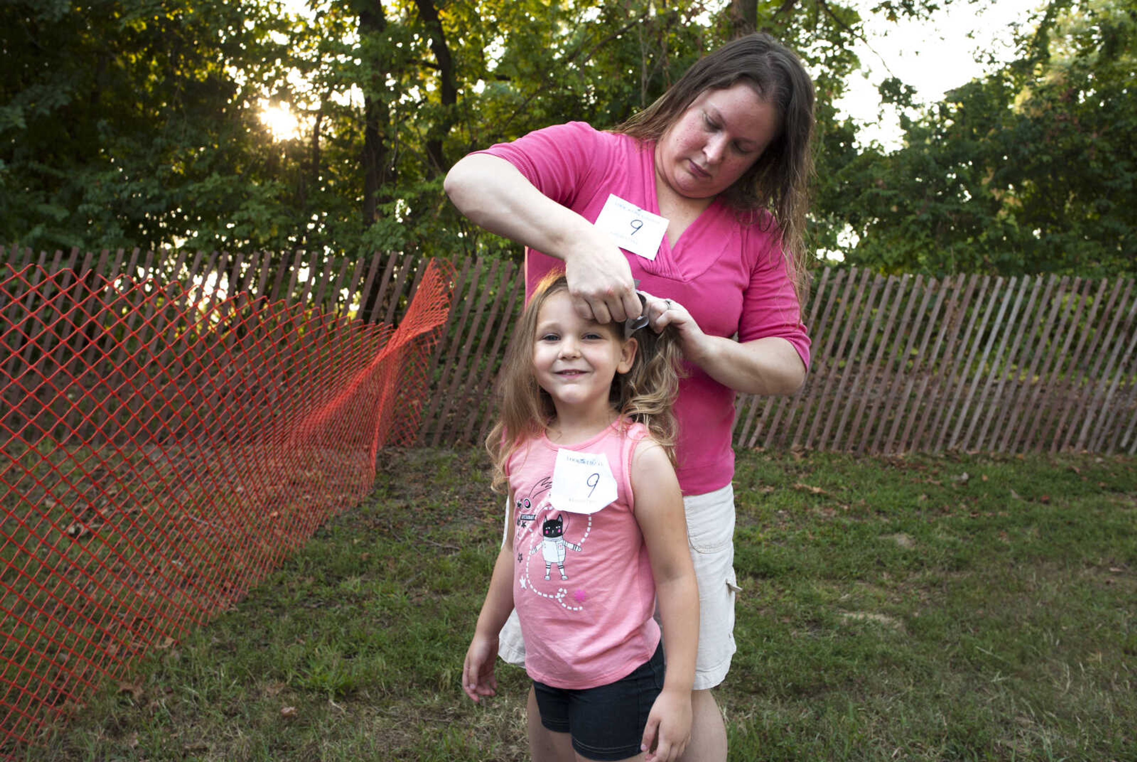 Cape Girardeau mother Stacy Beasley works to keep a bow in her four-year-old daughter Savannah's hair  as judges make their decisions in the Mother Daughter Lookalike contest Sept. 9, 2019, at the SEMO District Fair in Cape Girardeau.