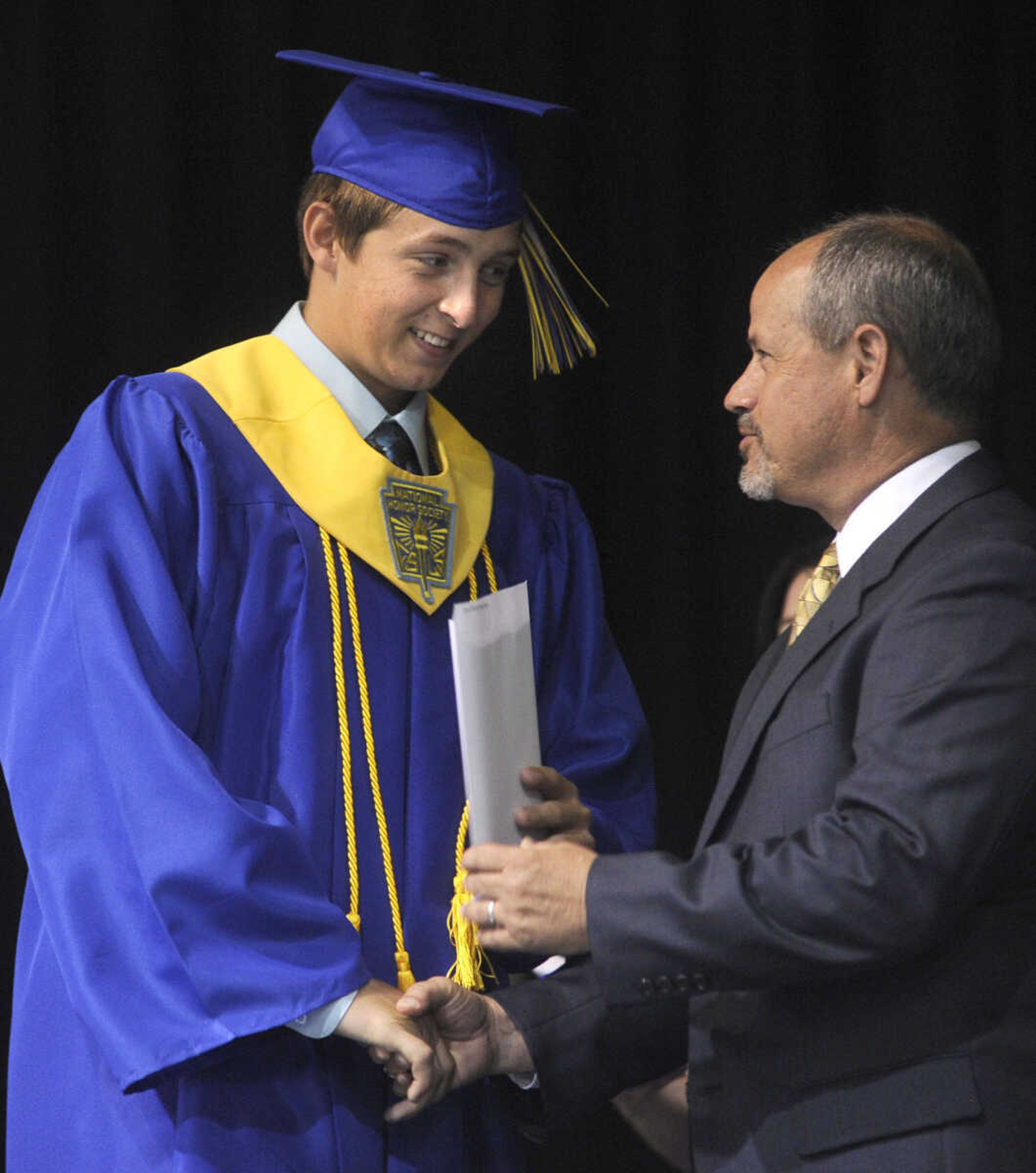 Ryan Brock receives his diploma from school board president Scott Amick.