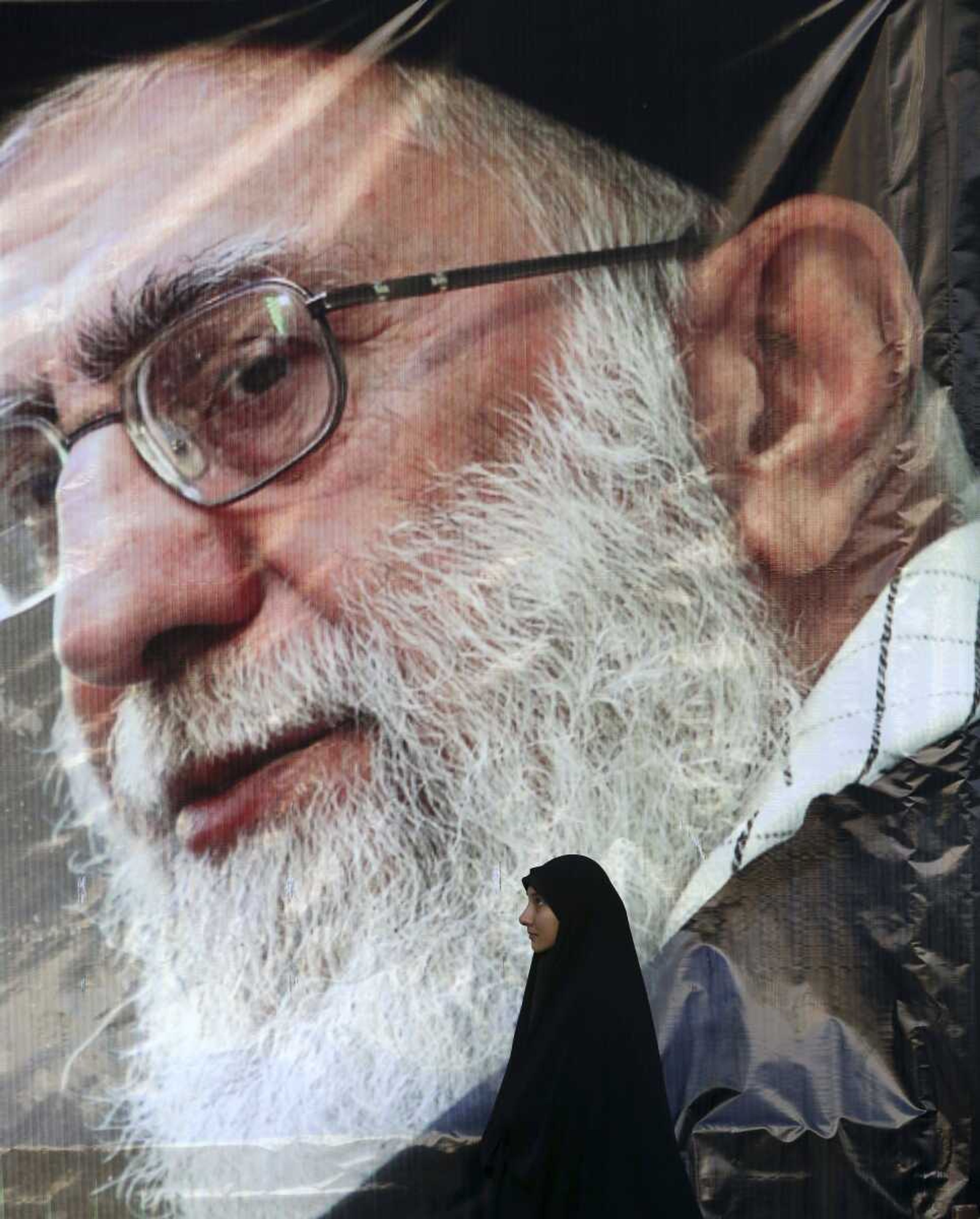 An Iranian woman stands under a portrait of the Supreme Leader Ayatollah Ali Khamenei at the conclusion of a rally Monday in Tehran, Iran, to protest the execution last week of Sheikh Nimr al-Nimr, a prominent opposition Shiite cleric, shown in the posters. (Vahid Salemi ~ Associated Press)