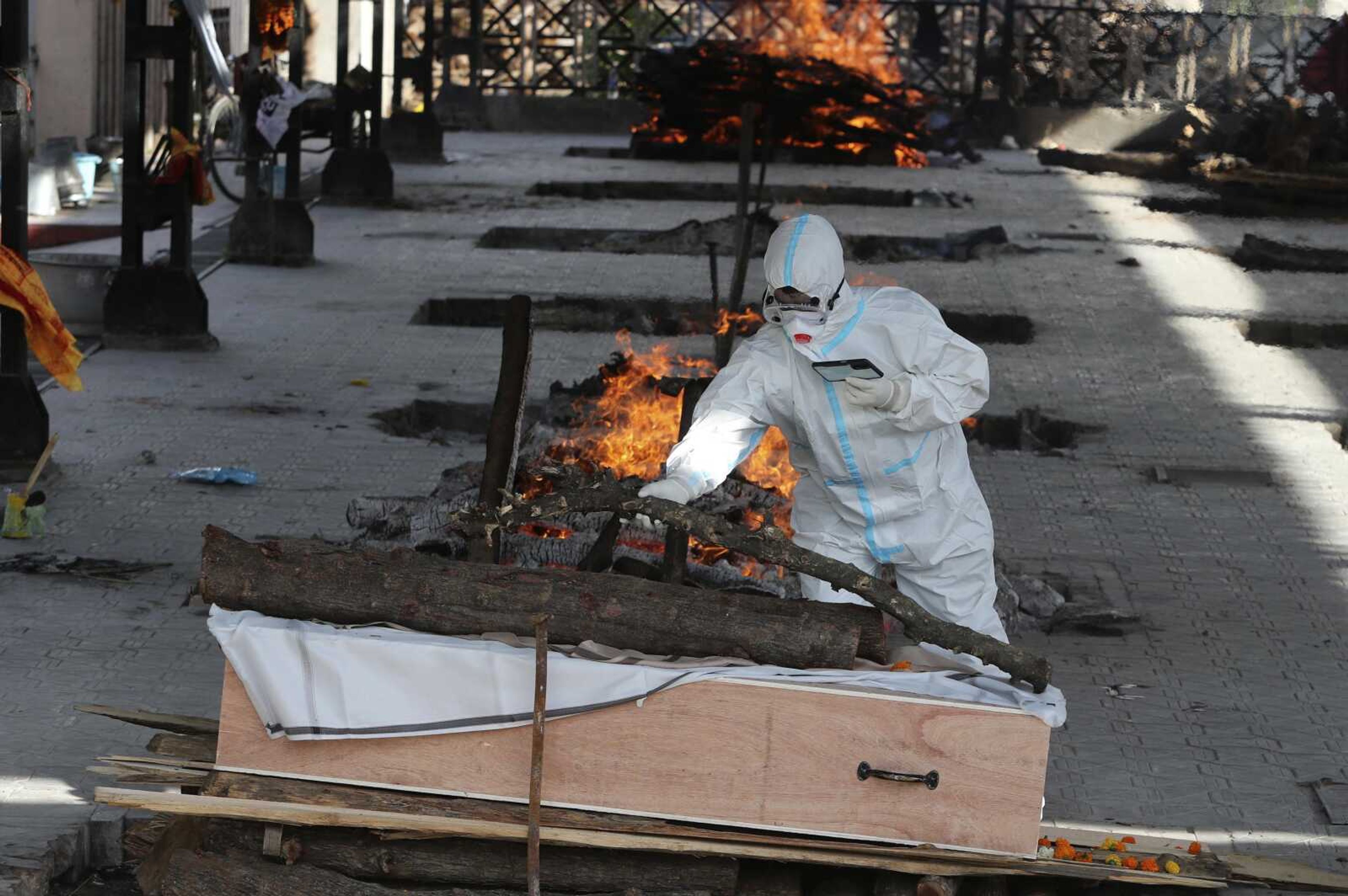 A man performs the final rites of a relative who died of COVID-19, at a crematorium in Jammu, India. India's underfunded health system is tattering as the world's worst coronavirus surge wears out the nation, which set another global record in daily infections for a second straight day with 332,730.