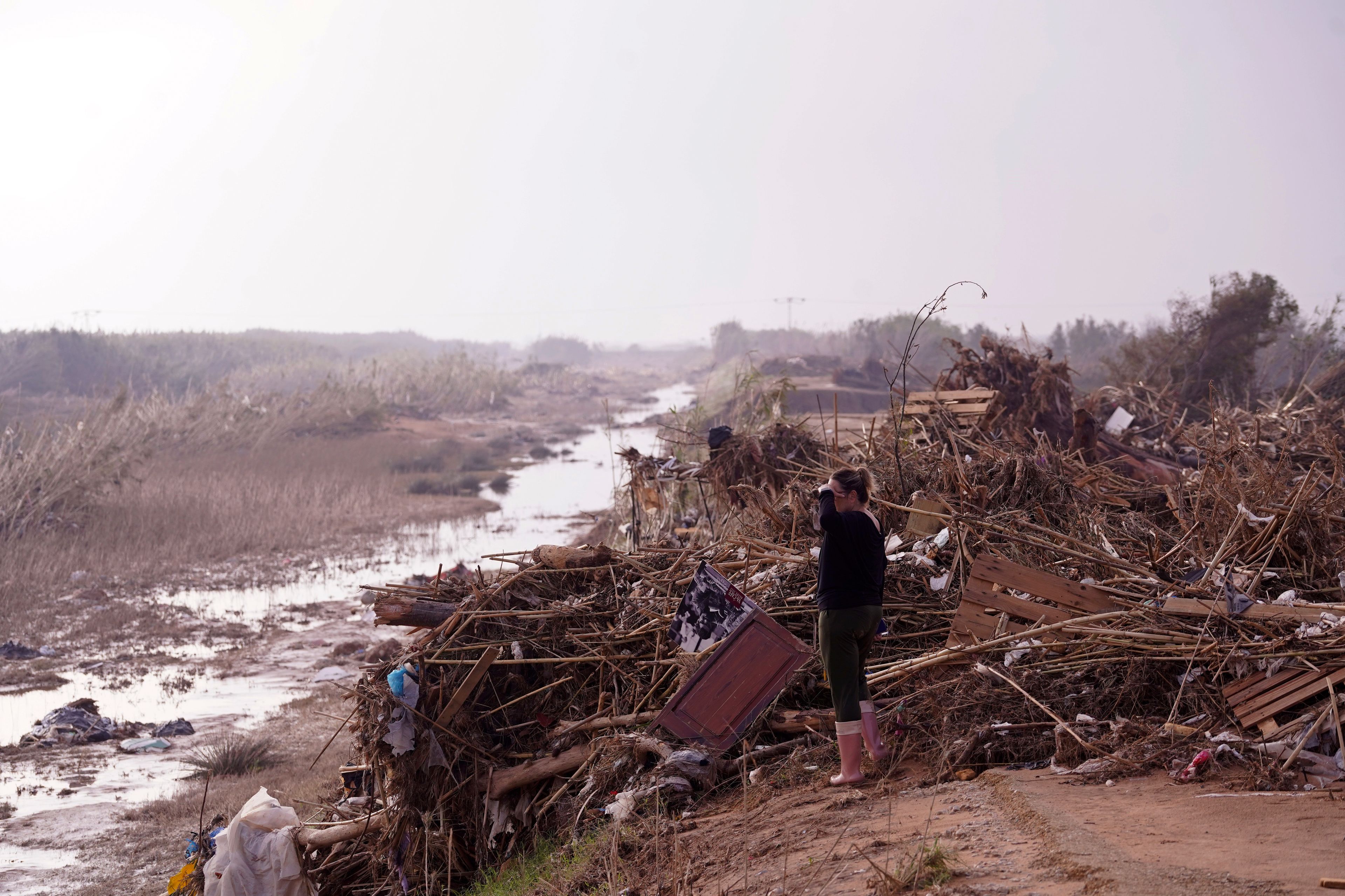 A woman looks out next to flood debris in Barranco de Chiva on the outskirts of Valencia, Spain, Wednesday, Nov. 6, 2024. (AP Photo/Alberto Saiz)