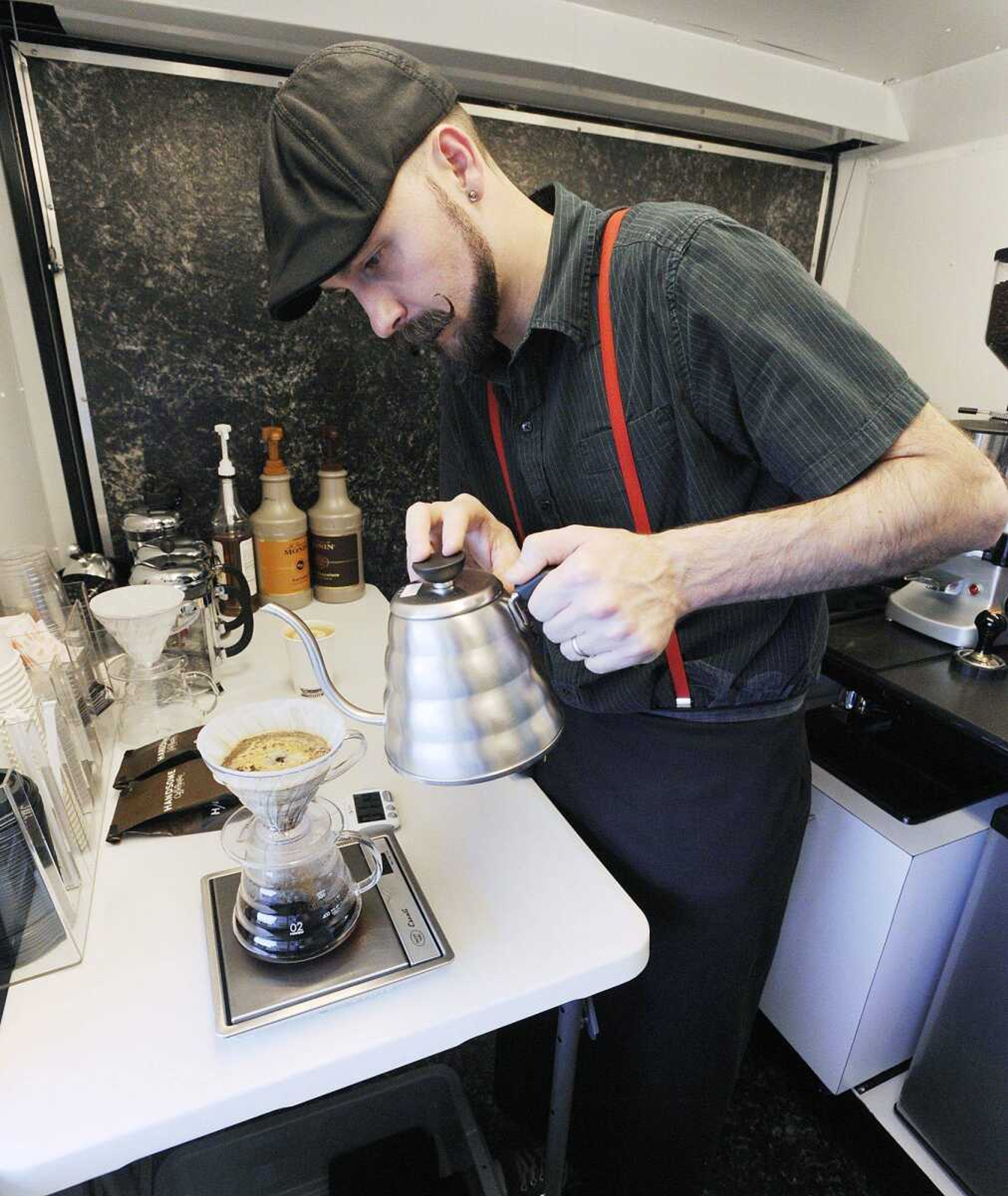 Dynamite Coffee owner Robbie Britt prepares a drip coffee at his coffee stand outside the main entrance of West Park Mall. Britt offers several coffee drinks as well as whole beans from his stand. (ADAM VOGLER)