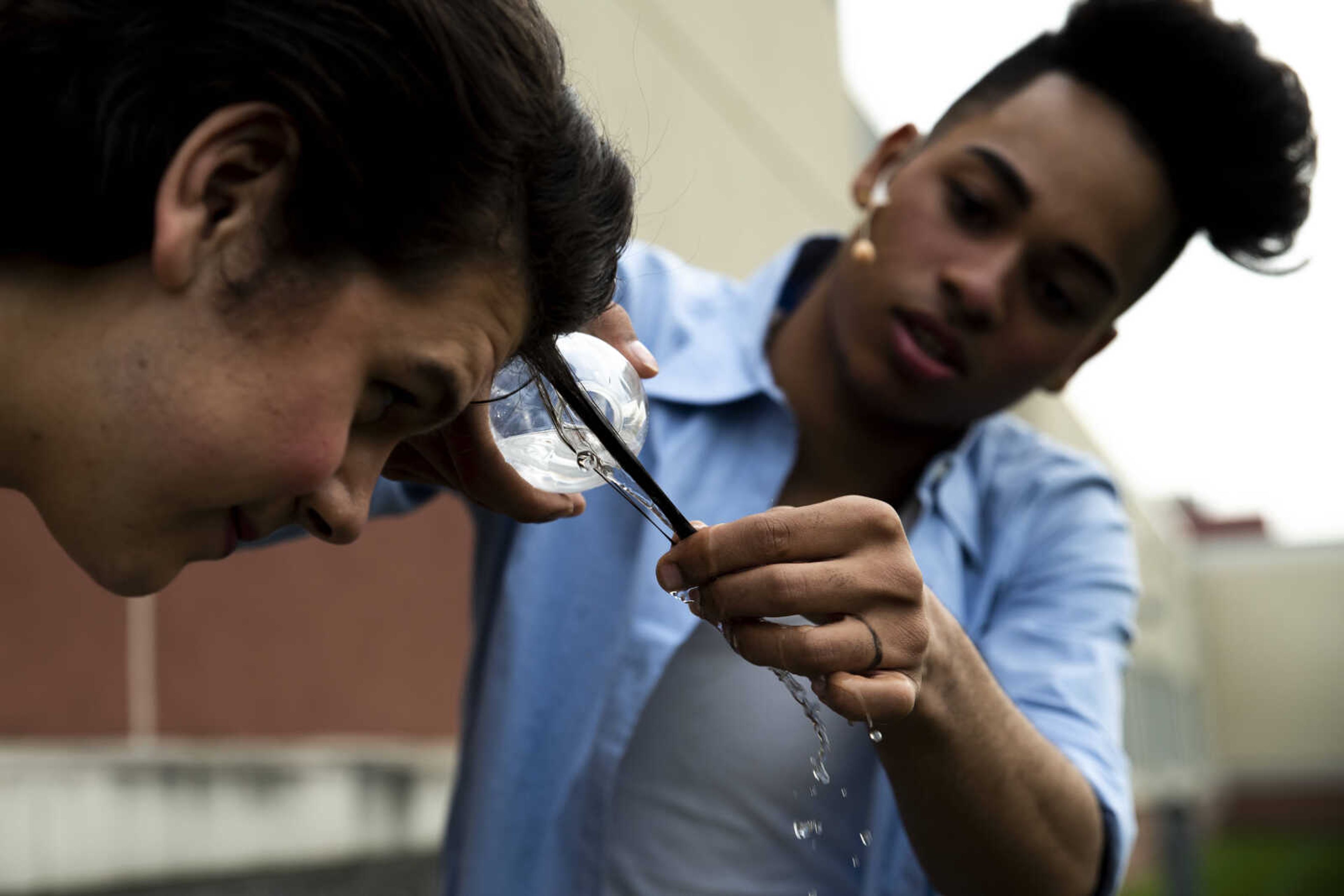 Timother Babers, left, watches as Izaiah Betancur pours water on a section of his hair to create a curl as he is transformed into his role of Pepper during the media night of Cape Central High School's spring musical production of "Mamma Mia!" Wednesday, April 10, 2019, in Cape Girardeau.