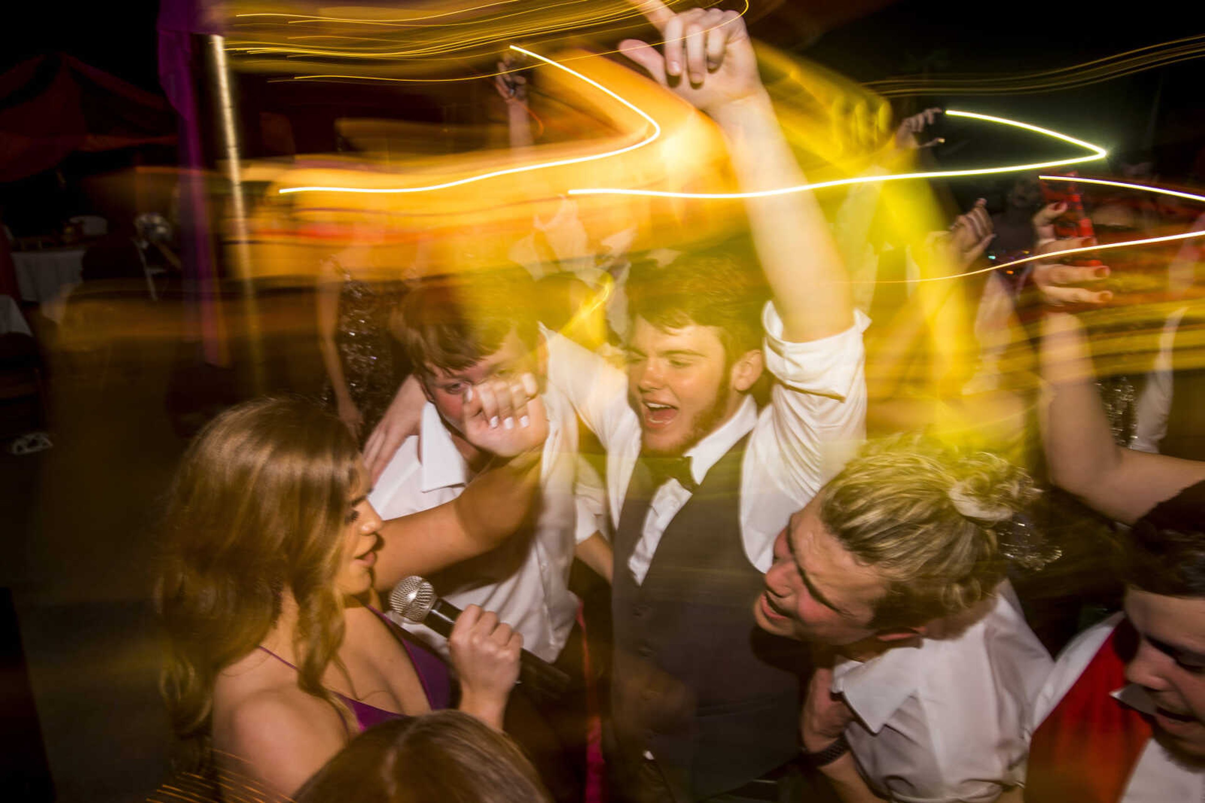 Lynsey Powers, left, sings Journey's "Don't Stop Believin'" while classmates sing along on the dance floor during prom Saturday, April 6, 2019, at Kelly High School in Benton.