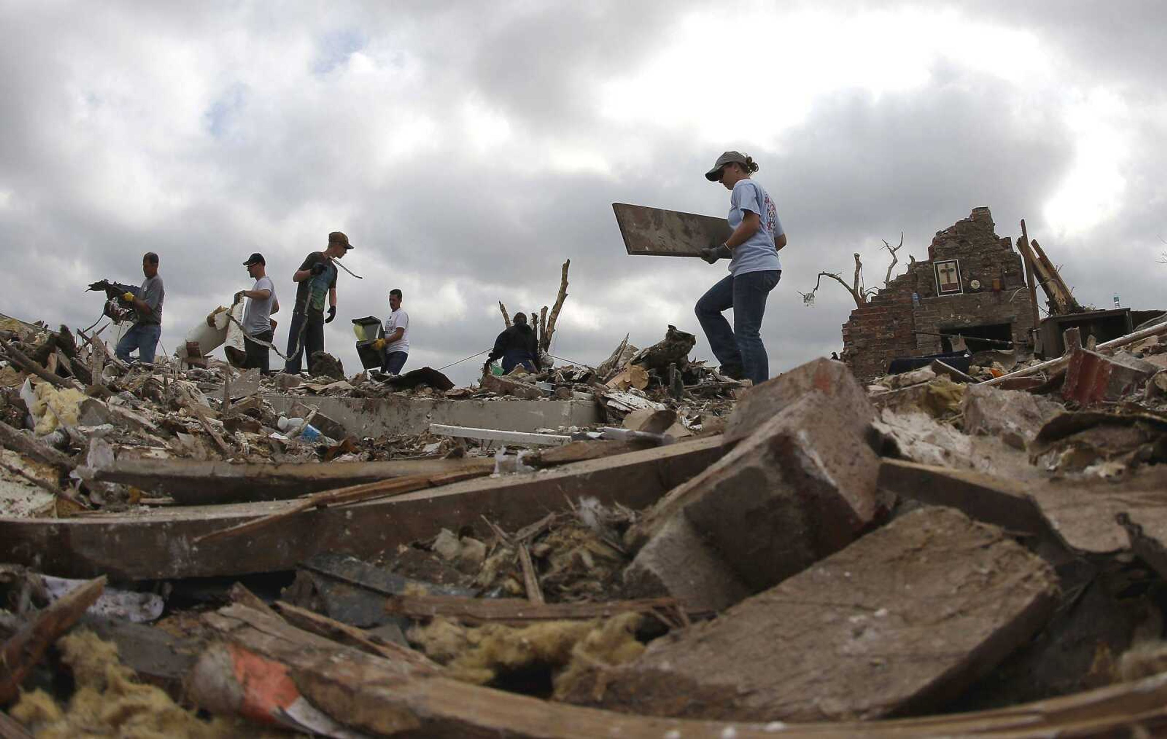 Abby Cotten, right, carries away debris Saturday while friends and family help her sort through the tornado-ravaged home she shared with her parents in Moore, Okla. Cleanup continues after a huge tornado roared through the Oklahoma City suburb Monday, flattening a wide swath of homes and businesses. (Charlie Riedel ~ Associated Press)