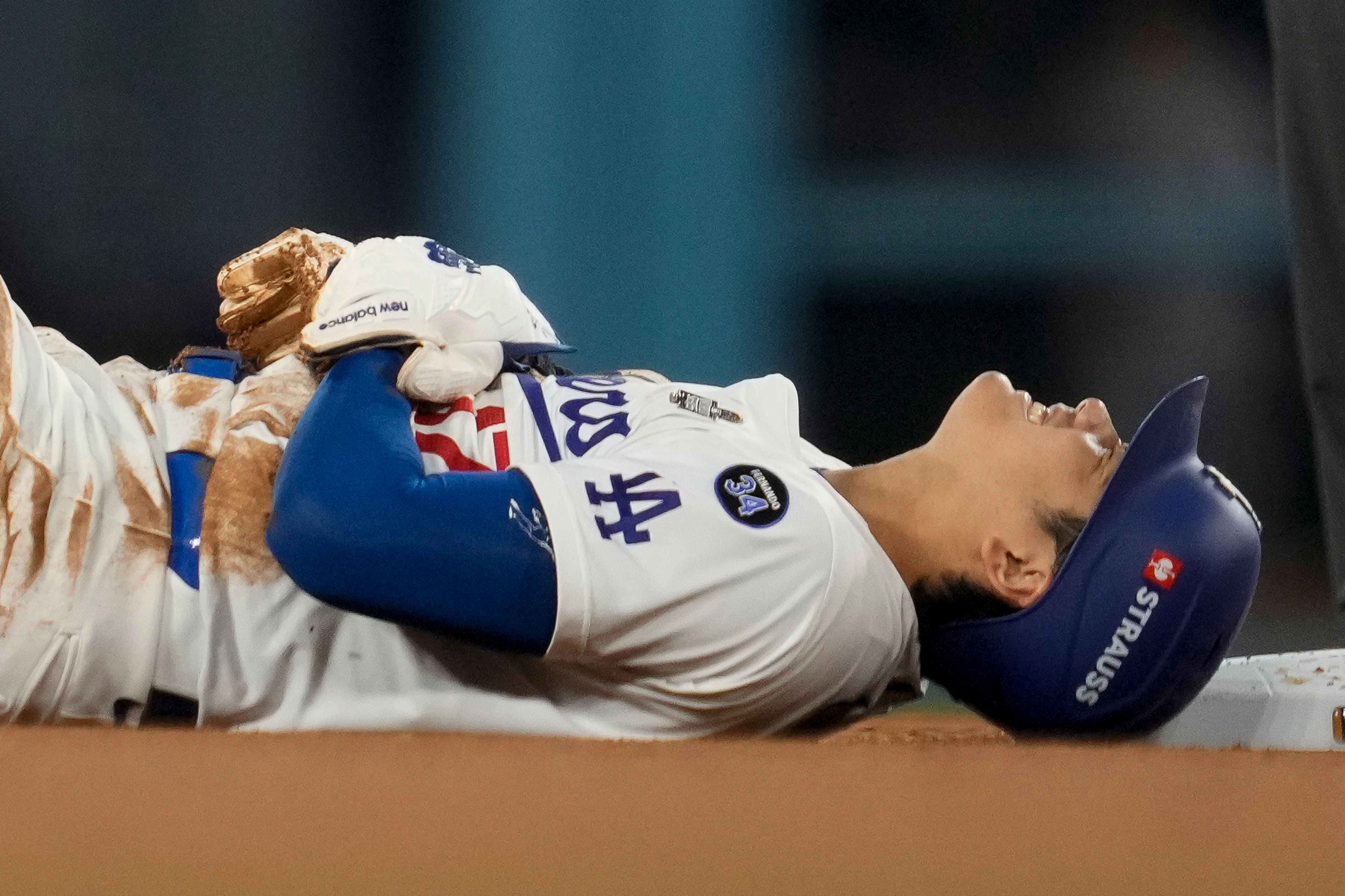 Los Angeles Dodgers' Shohei Ohtani holds his arm after being injured while attempting to steal second base during the seventh inning in Game 2 of the baseball World Series against the New York Yankees, Saturday, Oct. 26, 2024, in Los Angeles. (AP Photo/Ashley Landis)