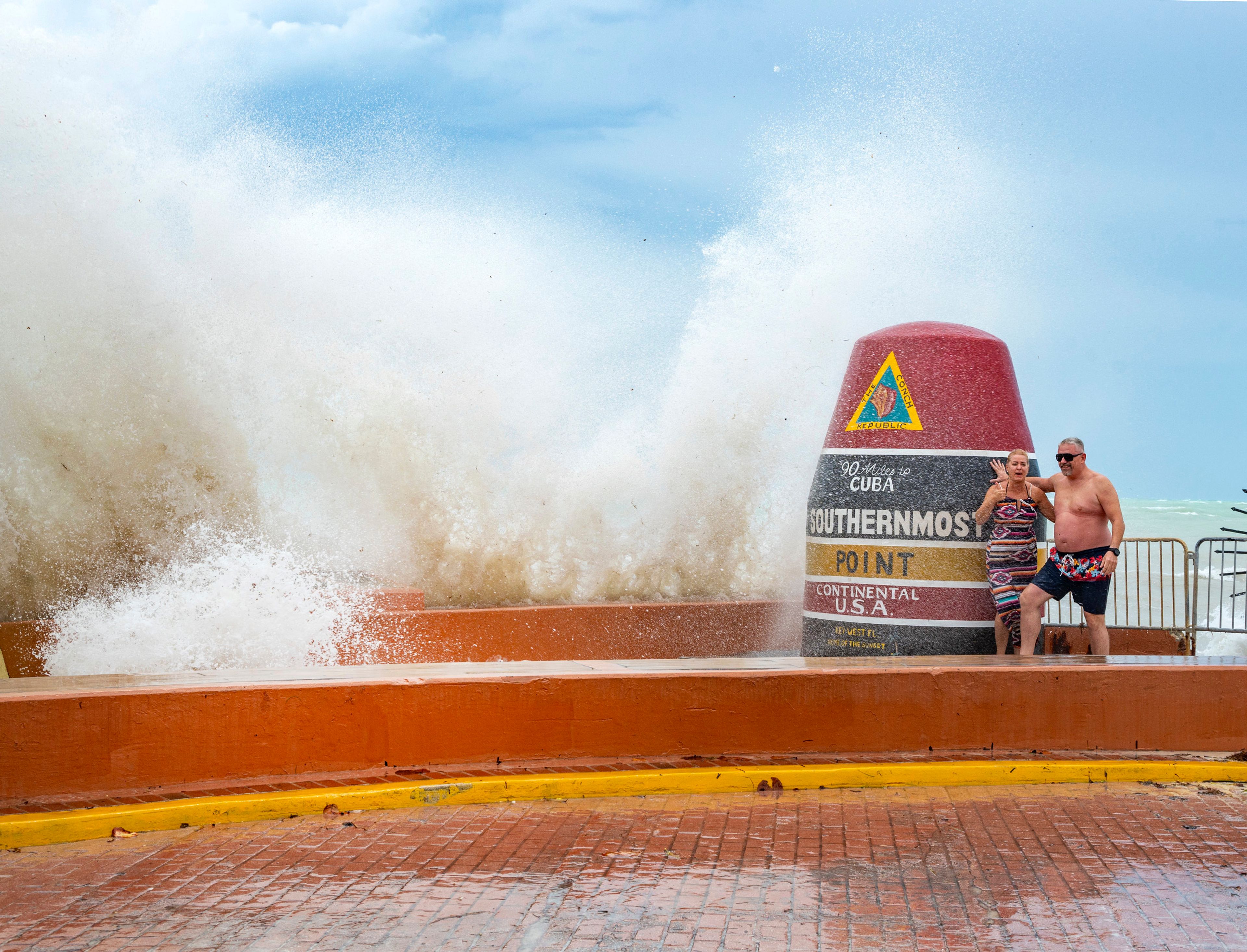 Visitors to the Southernmost Point marker in Key West, Fla., are hit by wind driven waves from approaching Hurricane Helene on Wednesday, Sept. 25, 2024. (Rob O'Neal/The Key West Citizen via AP)