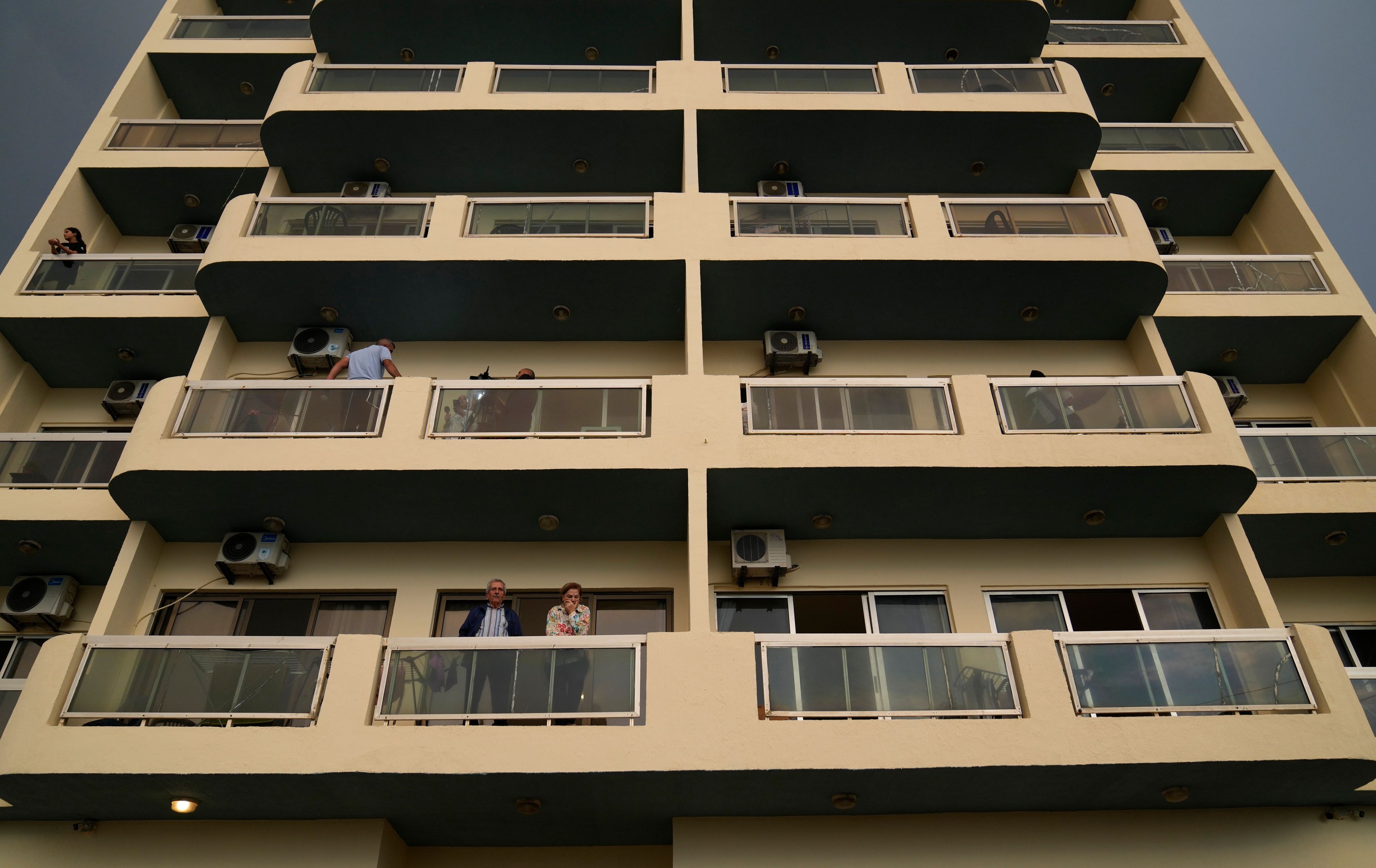 Residents stand on the balcony of a building in Batroun, northern Lebanon, Saturday, Nov. 2, 2024, where Lebanese officials say a ship captain was taken away by a group of armed men who landed on a coast north of Beirut and they're investigating whether Israel was involved. (AP Photo/Hussein Malla)