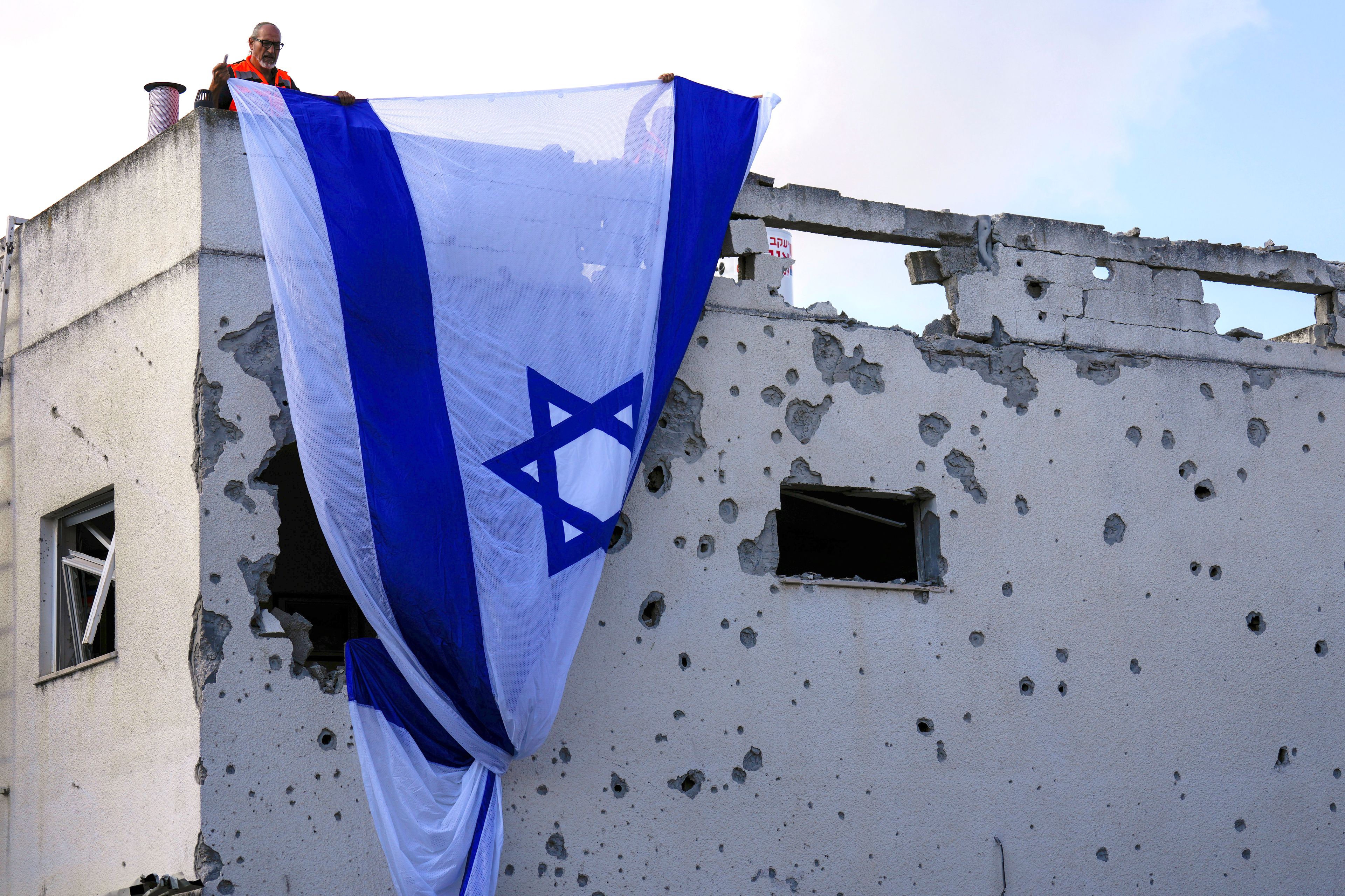 Municipality workers hang an Israeli flag over a damaged building that was hit by a rocket fired from Lebanon, in Kiryat Bialik, northern Israel, on Sunday, Sept. 22, 2024. (AP Photo//Ariel Schalit)