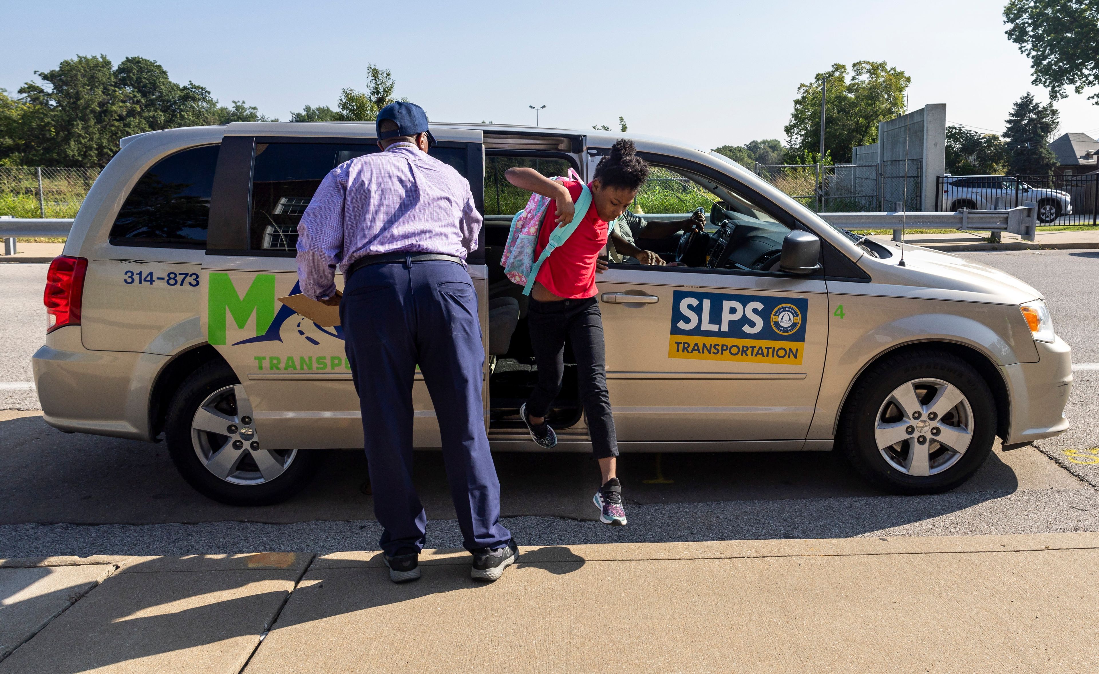 A student is helped out of a transportation service vehicle with a St. Louis Public Schools sign affixed to it, on the first day of school at Dewey Elementary in the Hi-Pointe neighborhood of St. Louis on Monday, Aug. 19, 2024. (Allie Schallert/St. Louis Post-Dispatch via AP)