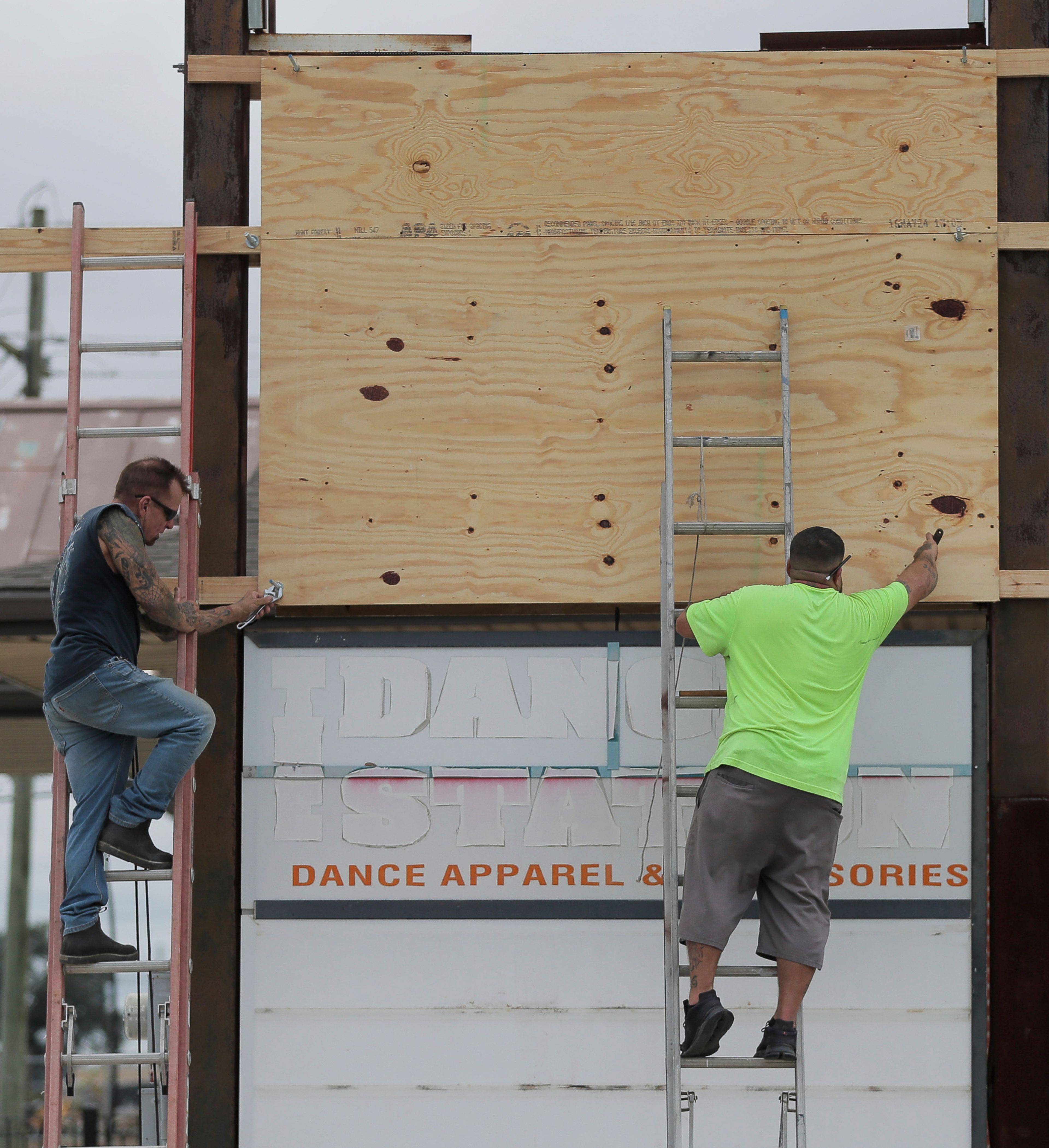 James C. McKenzie, left and Kelly Blanchard cover an electronic sign with plywood ahead of Tropical Storm Francine Monday, Sept. 9, 2024, in Chalmette, La.. (David Grunfeld/The Times-Picayune/The New Orleans Advocate via AP)