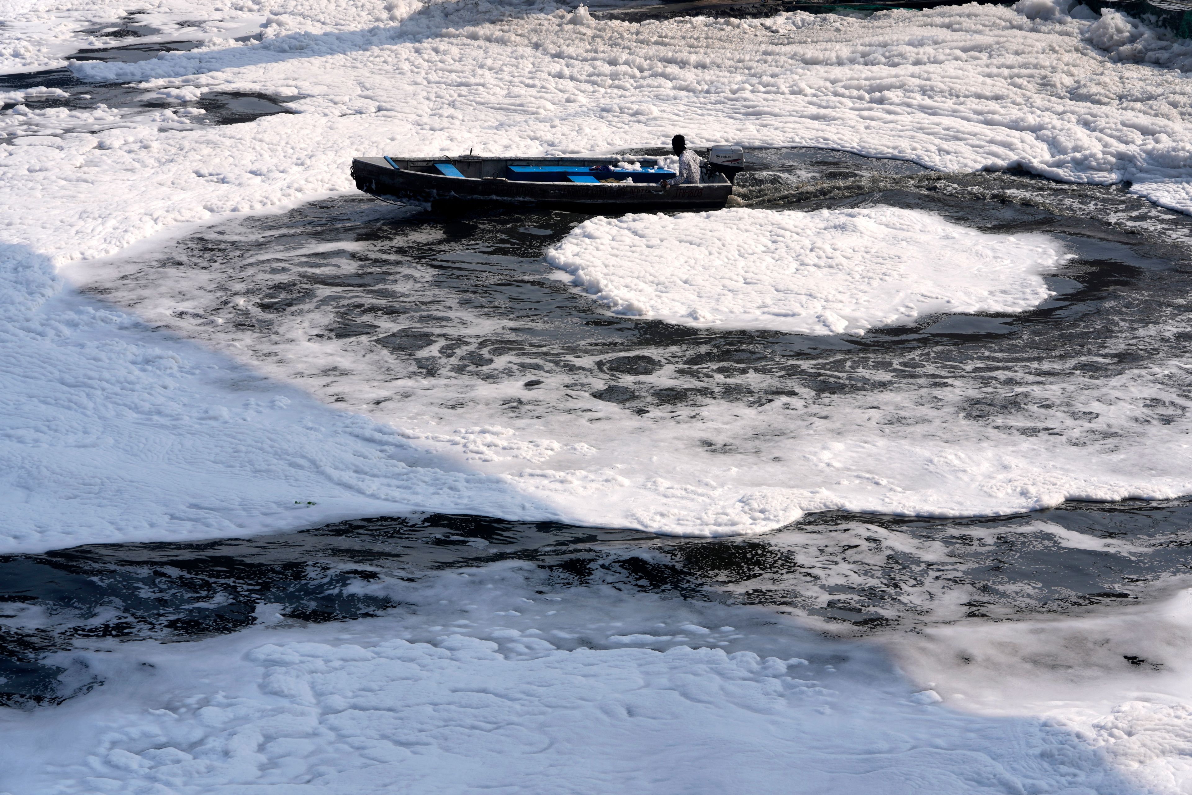 A worker for the Delhi Jal or water board moves his boat in circular pattern to cut the flow of toxic foams flowing in the river Yamuna in New Delhi, India, Tuesday, Oct. 29, 2024. (AP Photo/Manish Swarup)