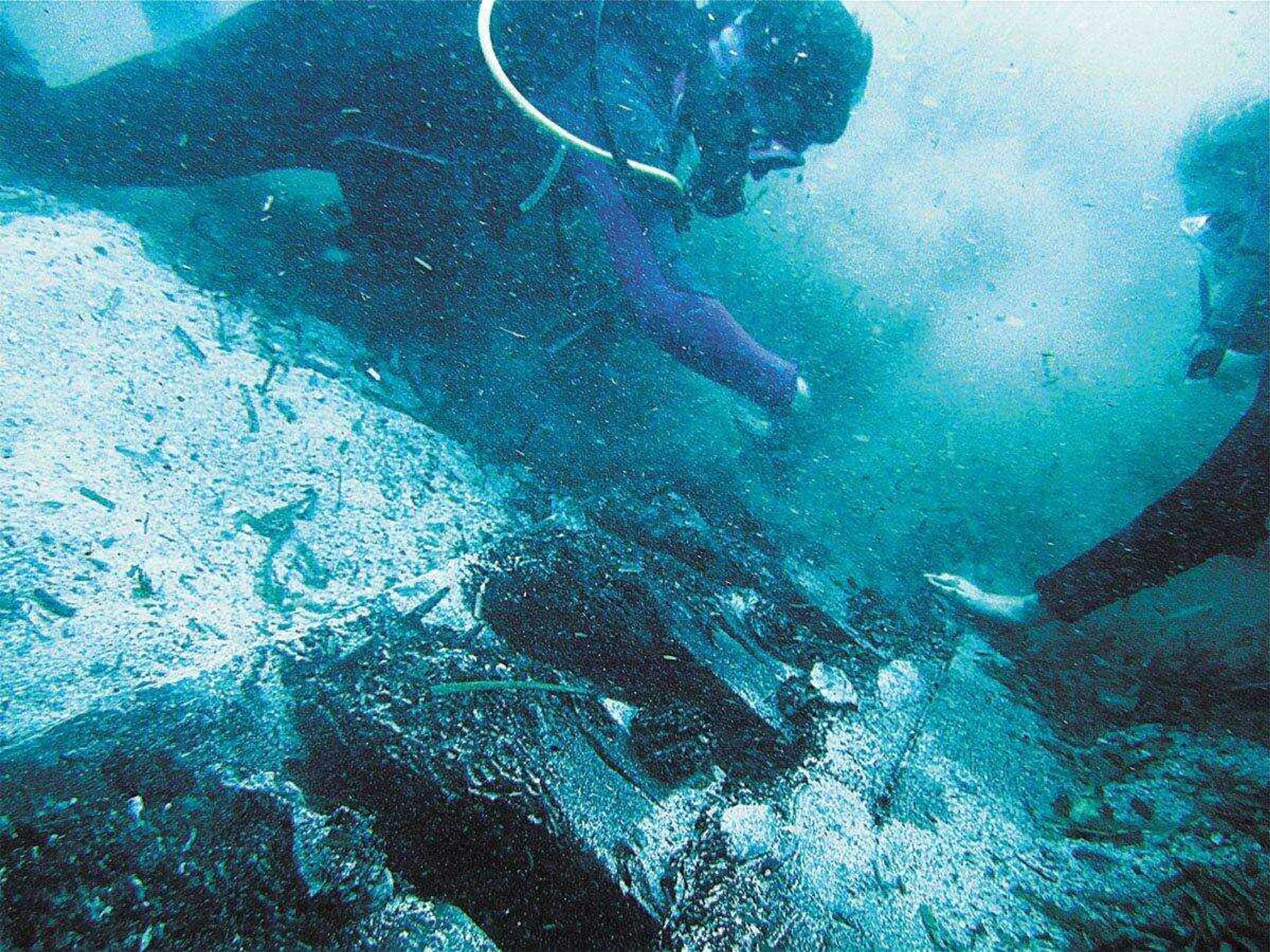 Jennifer Rickard, left, and a fellow crew member brush seaweed and sediment from the hull of the ship.