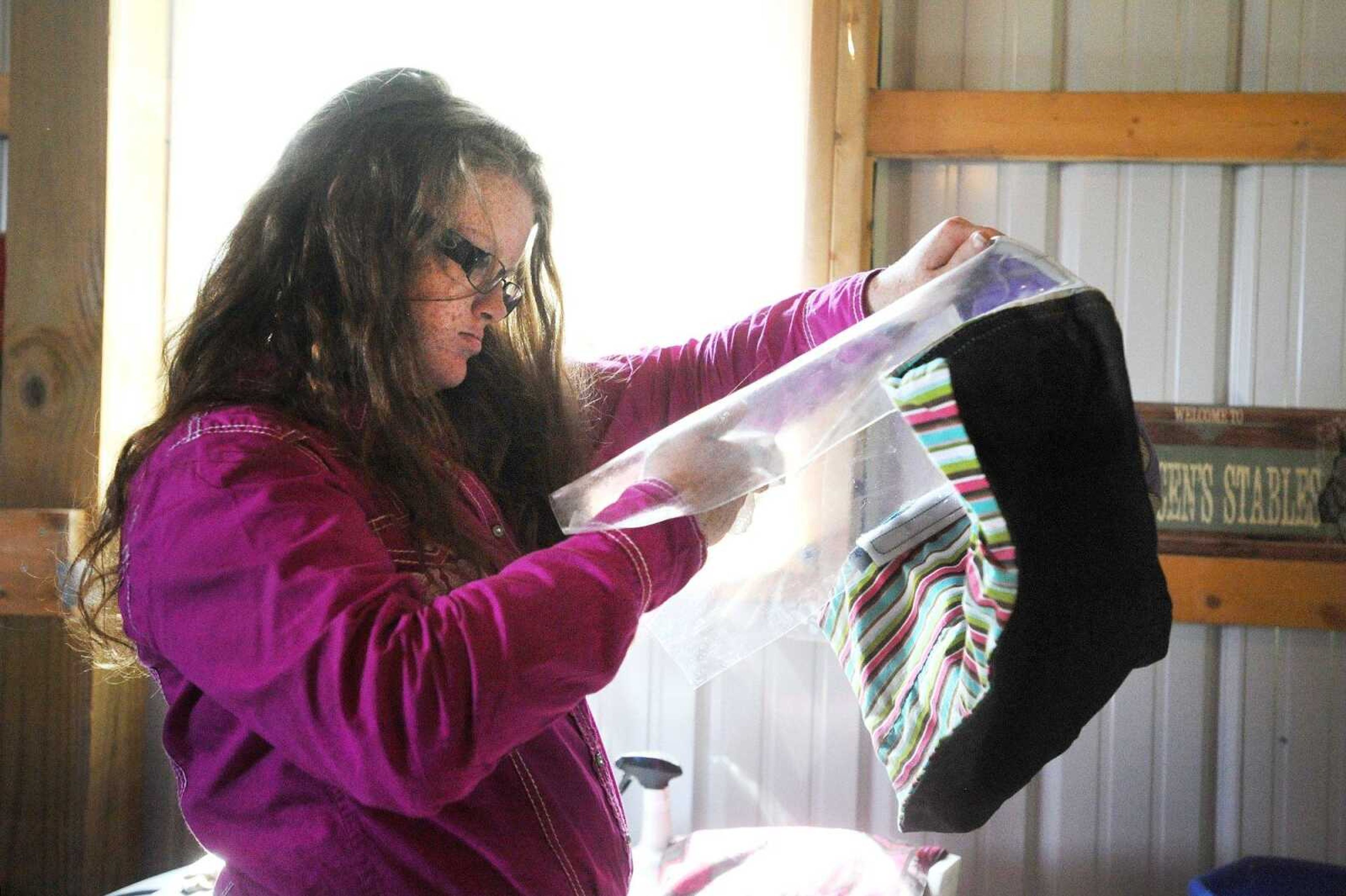 Graycen Beardslee, 13, uses glass cleaner to clean the inside of her hood, Aug. 7, 2015. Beardslee has a condition commonly referred to as XP, a genetic disorder less commonly known as Xeroderma Pigmentosum, that disables her body from repairing skin damaged by ultraviolet rays. The special type of plastic on her hood blocks her face and neck from UV rays. (Laura Simon)