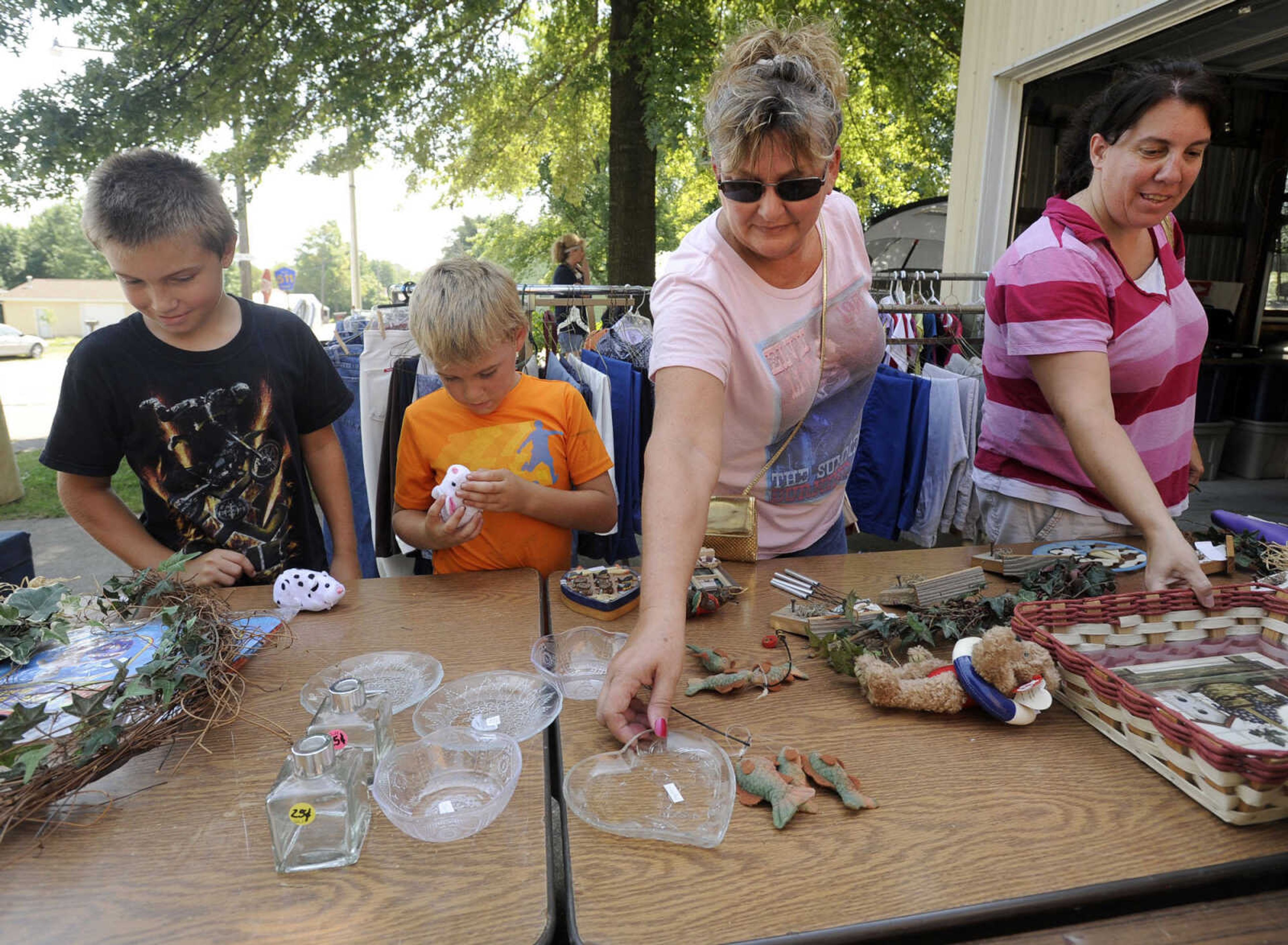 Jay Jannin, left, Tyler Jannin, Tonya Jannin, right, all of Perryville, Mo., and Karen Foster of Allenville, Mo. look at items offered for sale along the Highway 61 Yard Sale Saturday, Aug. 31, 2013 in Longtown, Mo.