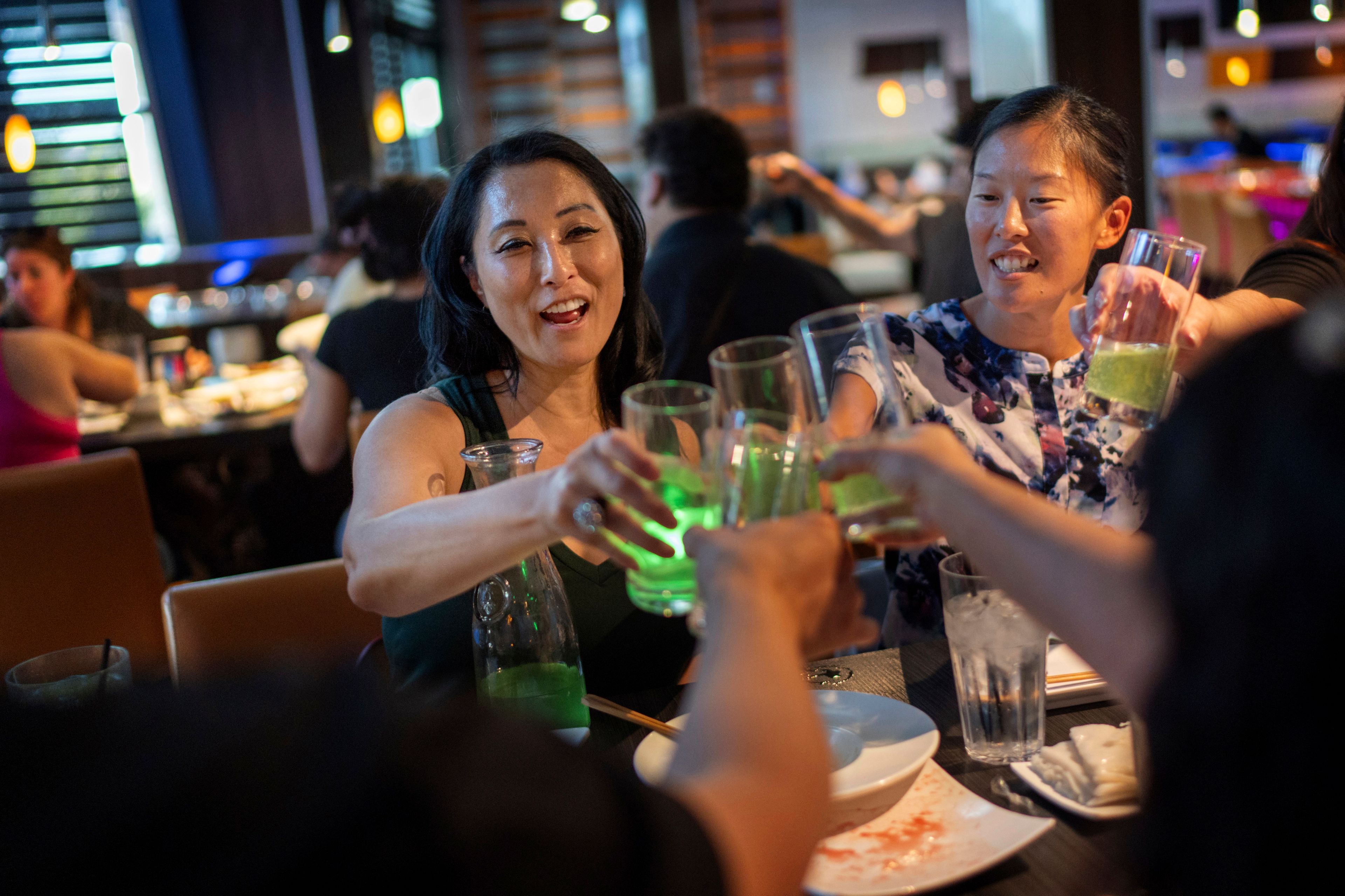 Joy Alessi, left, and Leah Elmquist toast during a dinner with fellow adoptees Sunday, June 23, 2024, in Las Vegas. Alessi and Elmquist have found strength in the community of adoptees who only learned as adults they were never citizens. (AP Photo/David Goldman)