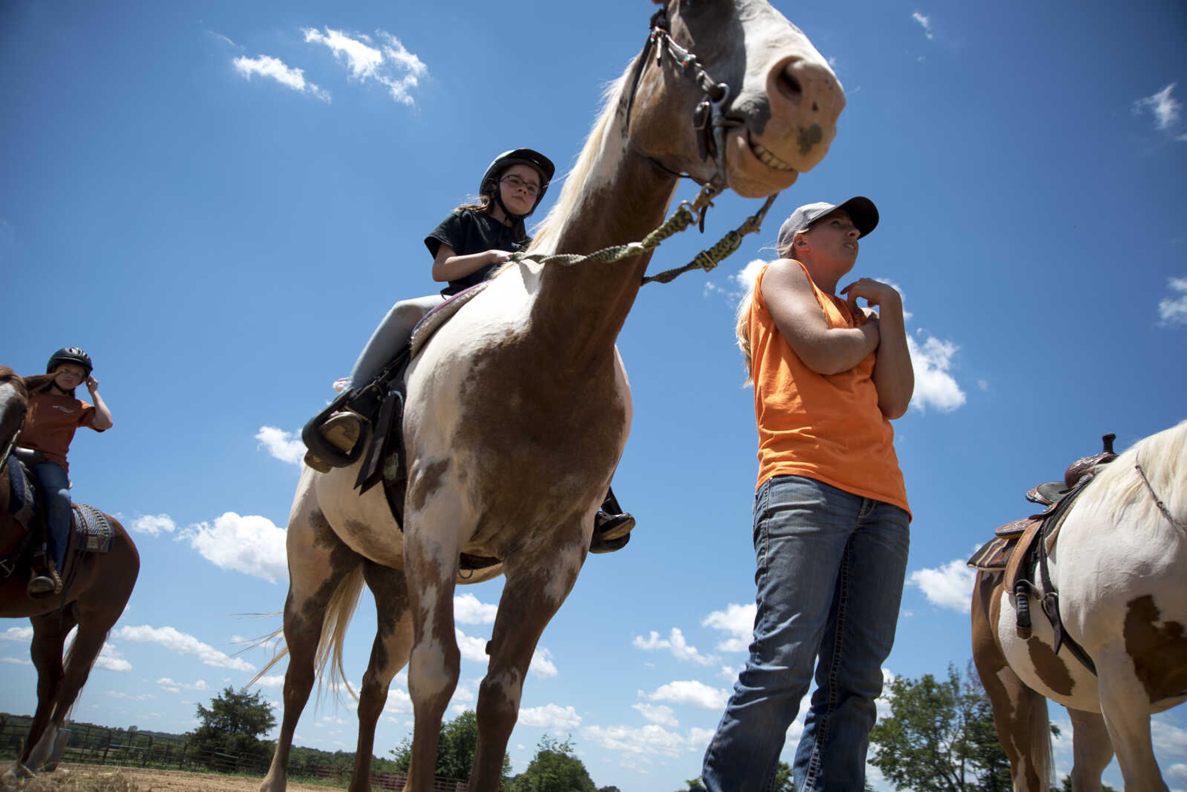 Serenity Glasser, 10, center, sits up on her horse while Kristin Carlton goes over instructions during the Rolling Hills Youth Day Camp Wednesday, June 7, 2017 in Cape Girardeau.