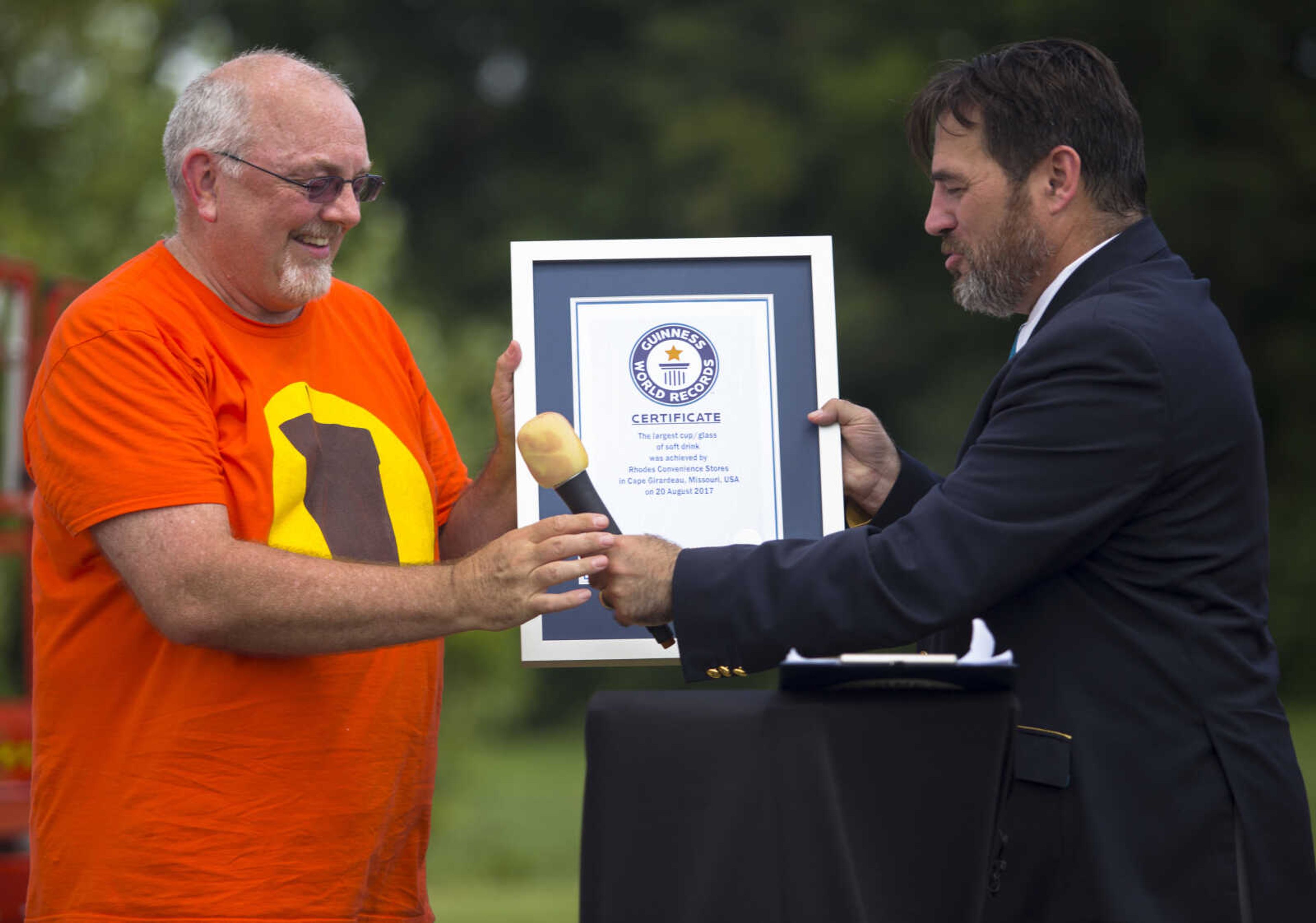 Guinness adjudicator Jimmy Coggins, right, presents a the Guinness World Record certificate for largest cup/glass of soft drink to Rhodes 101 Stop vice-president of information management Duane Statler at Mercato di Rodi in Cape Girardeau Sunday afternoon.