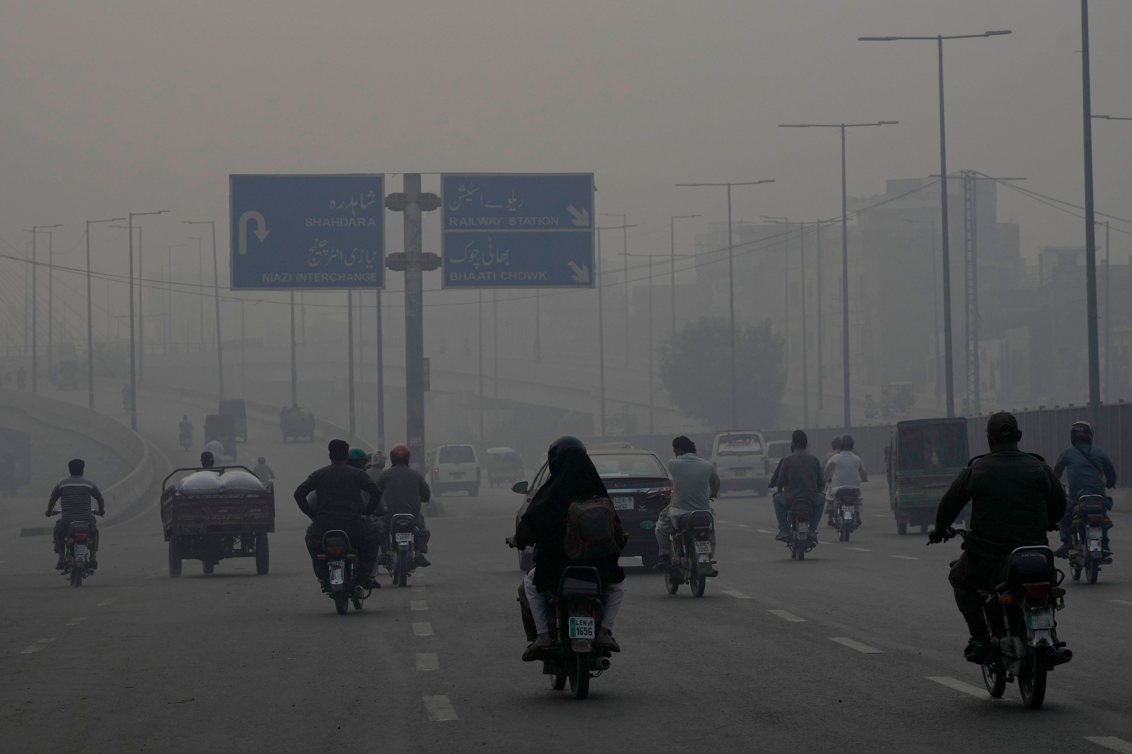 Motorcyclists drive on a highway as smog envelops the areas of Lahore, Pakistan, Wednesday, Nov. 6, 2024. (AP Photo/K.M. Chaudary)