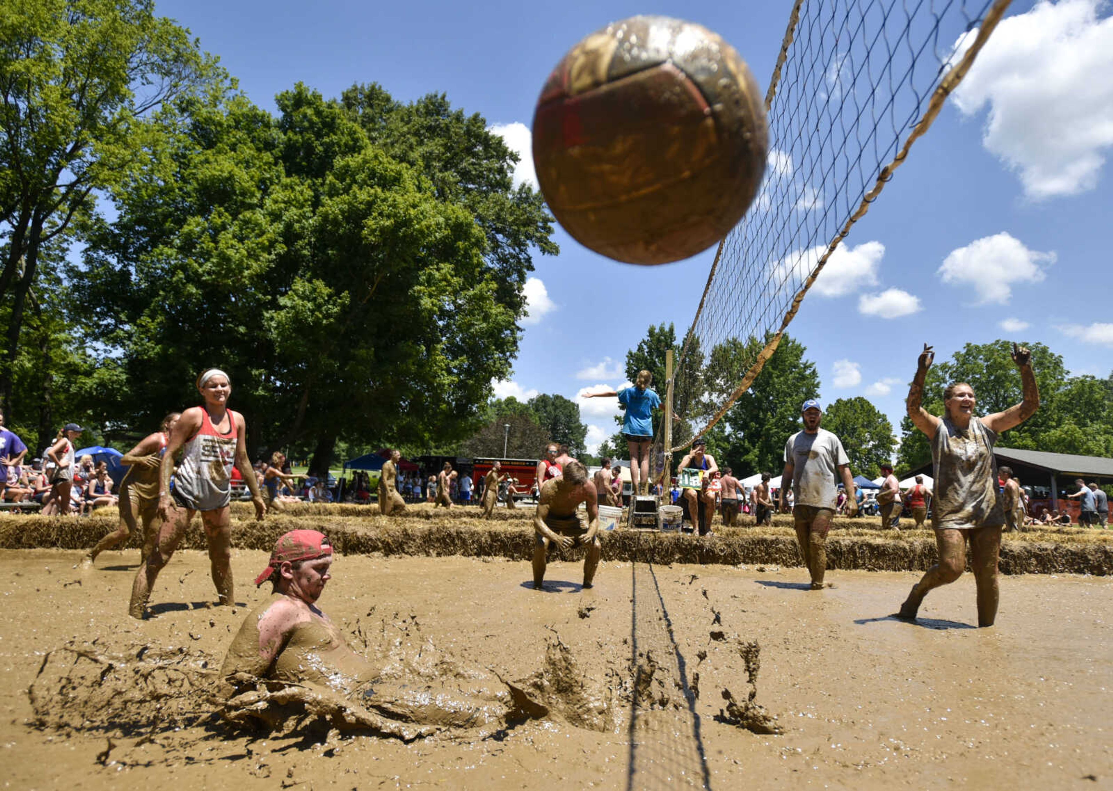 Mud volleyball players react to the winning point in a match as Drew Bartels, lower left, misses a diving attempt to keep the ball in play Wednesday, July 4, 2018, at Jackson City Park.