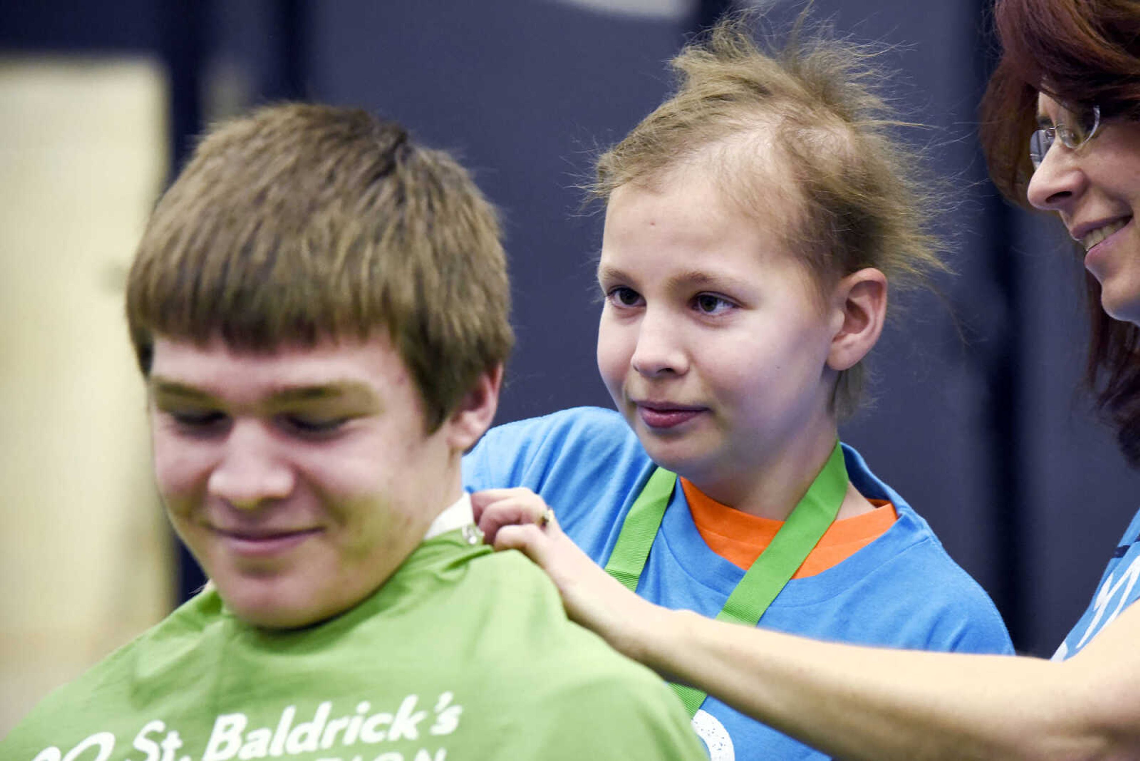 Sarah Singleton, 13, shaves part of her brother's, Justin, head with some assistance from April Whiteside on Saturday, March 4, 2017, during the St. Baldrick's Foundation fundraiser at Old Orchard CrossFit in Jackson.