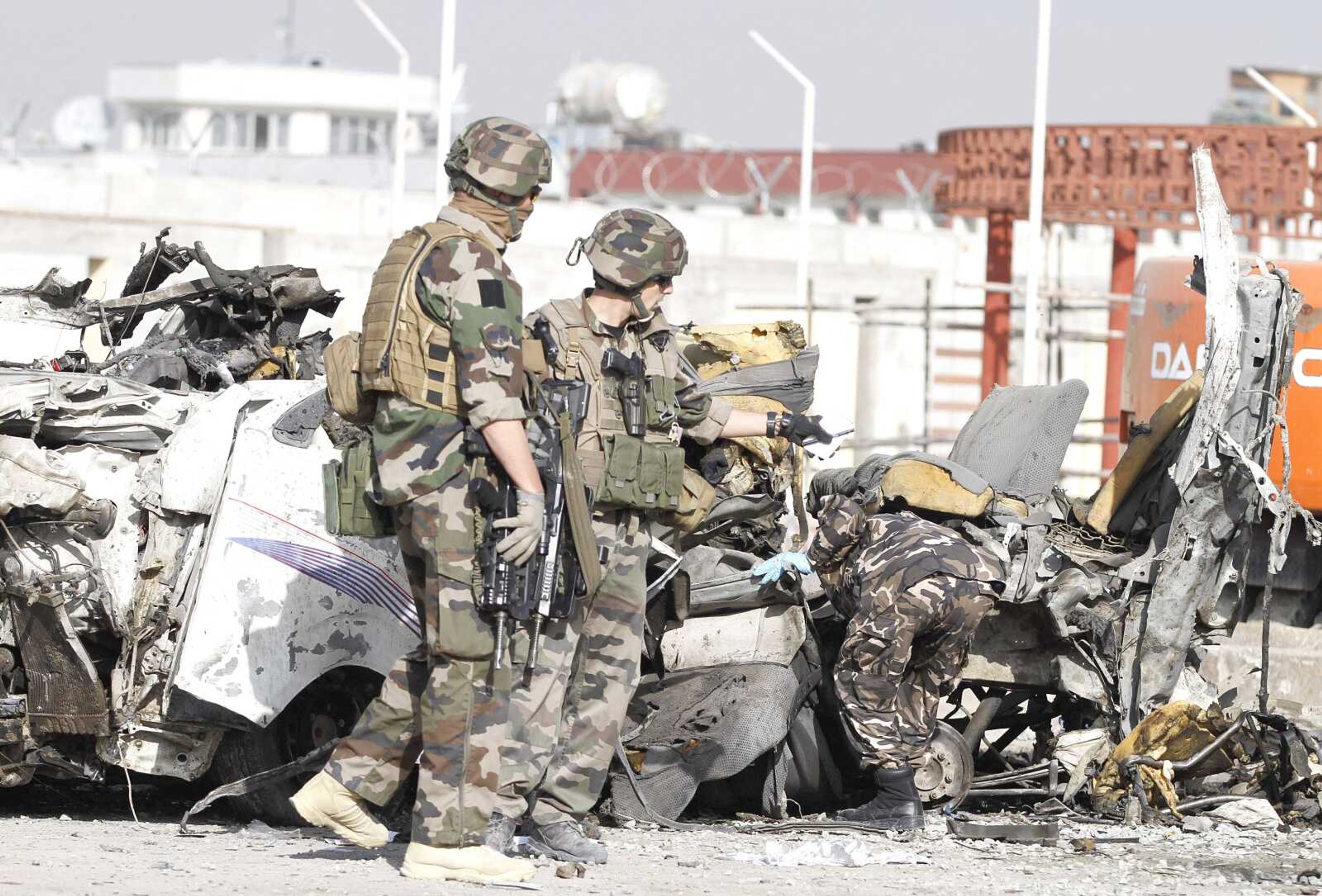 French soldiers arrive Tuesday at the scene of a suicide bombing in Kabul, Afghanistan. A suicide bomber rammed a car packed with explosives into a minibus carrying foreign aviation workers to the airport in the Afghan capital early Tuesday, killing at least 12 people in an attack a militant group said was revenge for an anti-Islam film that ridicules the Prophet Muhammad. (Ahmad Jamshid ~ Associated Press)