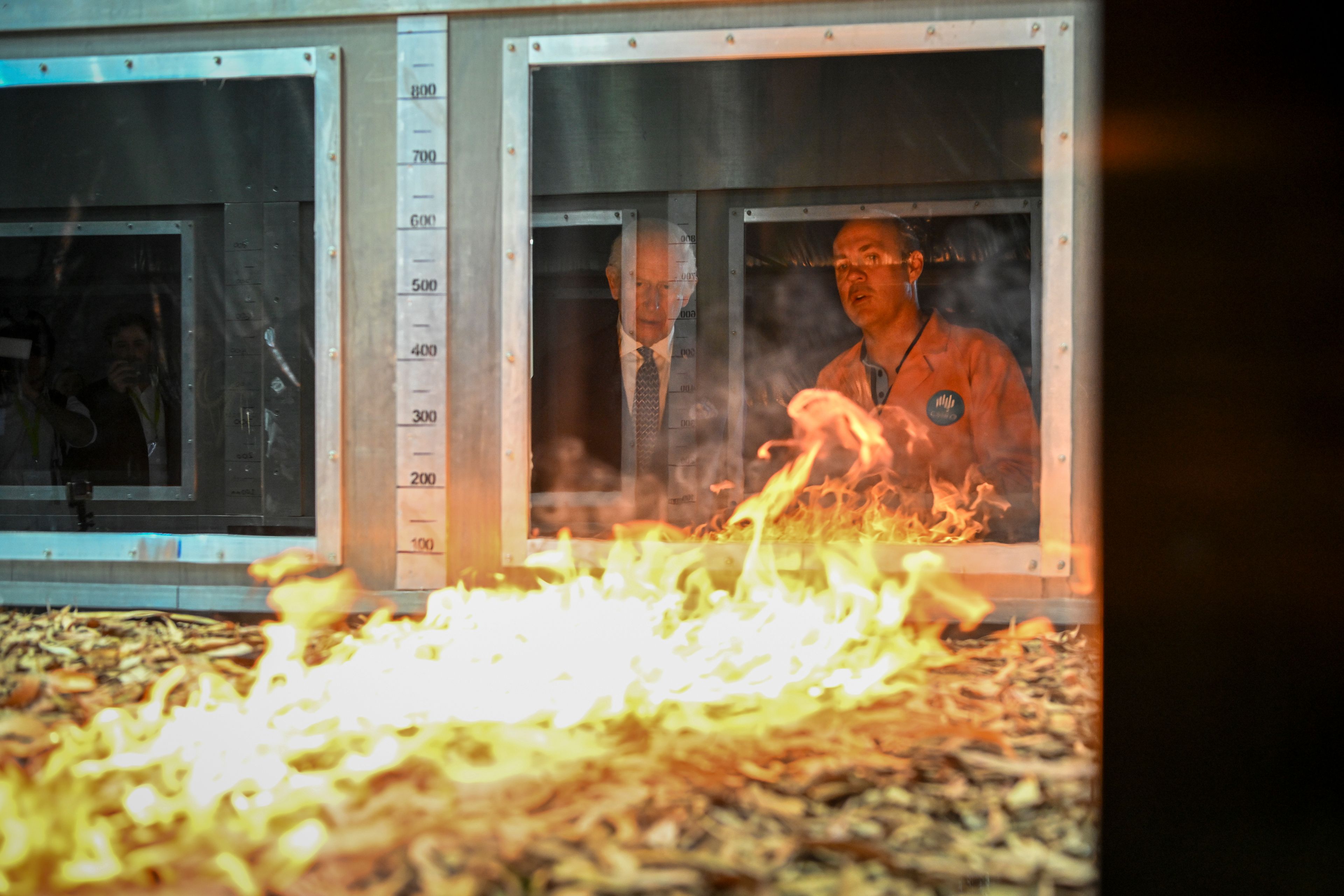 Britain's King Charles III listens to research scientist Dr. Matt Plucinski, right, describe the "Pyrotron" combustion wind tunnel during a visit to the CSIRO National Bushfire Behaviour Research Laboratory in Canberra, Monday, Oct. 21, 2024. (AP Photo/Tracey Nearmy, Pool)