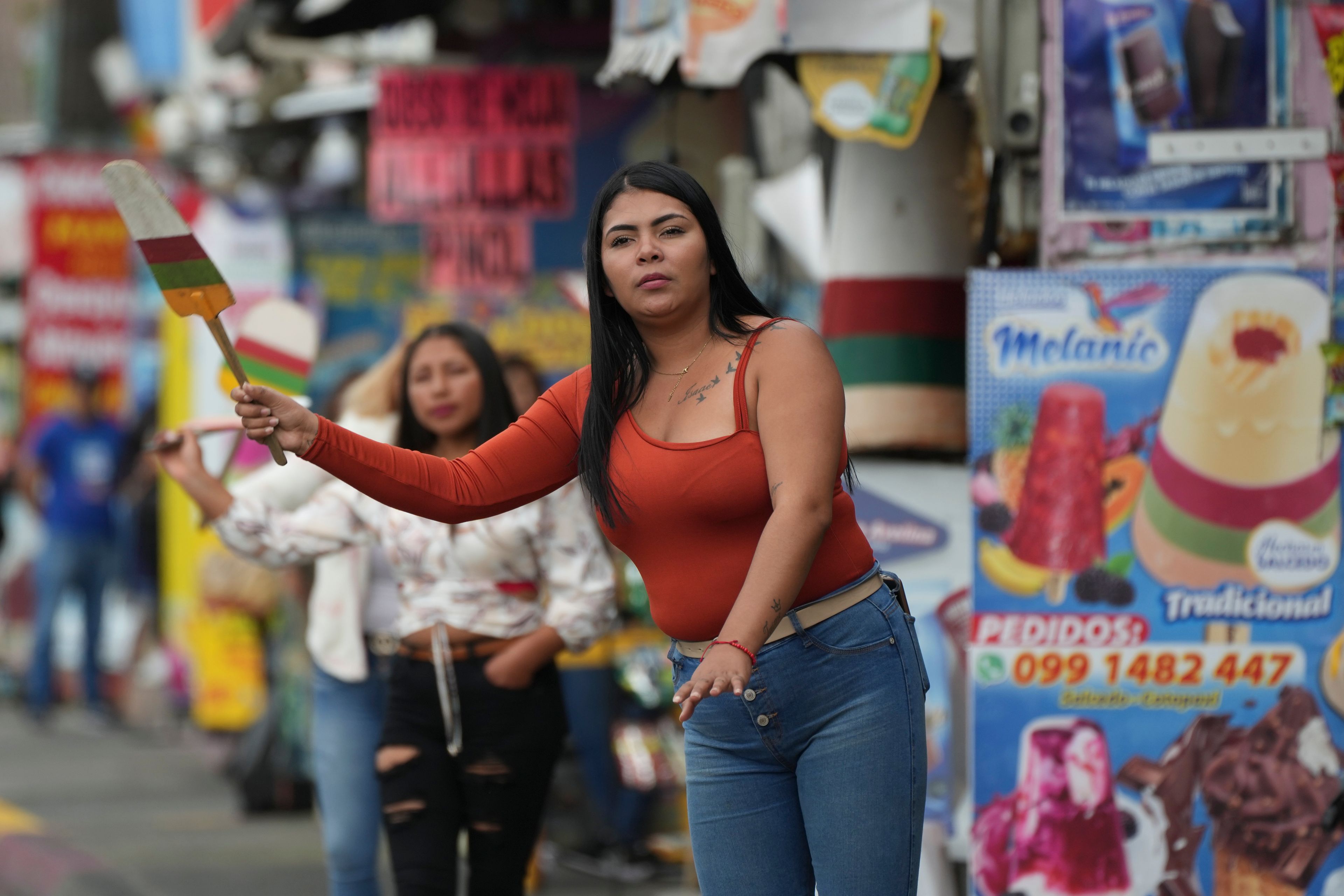 A vendor waves a popsicle-shaped sign to attract prospective customers in Salcedo, Ecuador, Thursday, Nov. 28, 2024, amid a wave of power outages, triggered by a prolonged dry spell. (AP Photo/Dolores Ochoa)