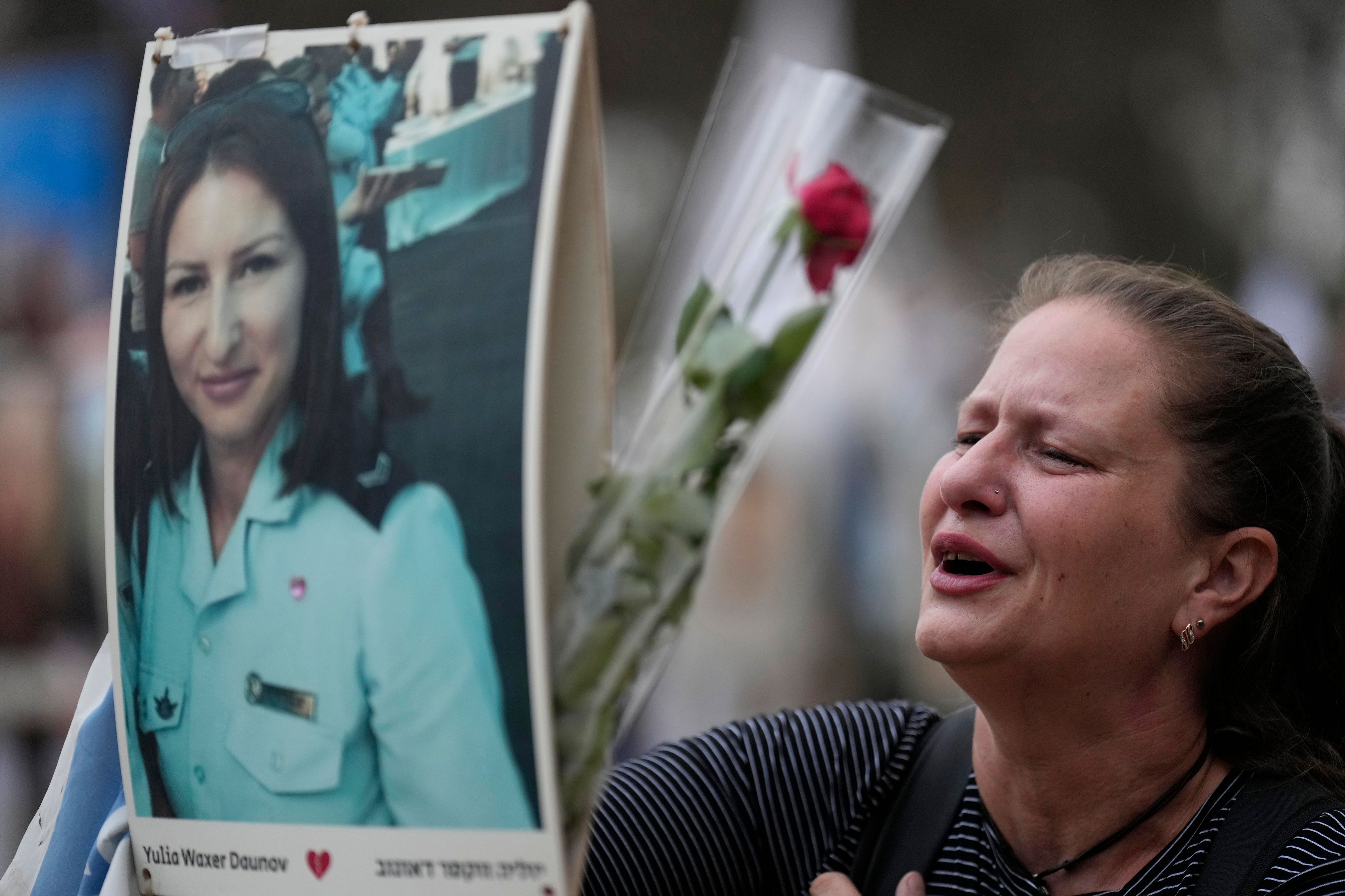 Victoria stands in front a picture of her sister, Yulia Waxer Daunt, as she visits the site of the Nova music festival, where hundreds of revelers were killed and abducted by Hamas and taken into Gaza, on the one-year anniversary of the attack, near Kibbutz Reim, southern Israel, Monday, Oct. 7, 2024. (AP Photo/Ariel Schalit)