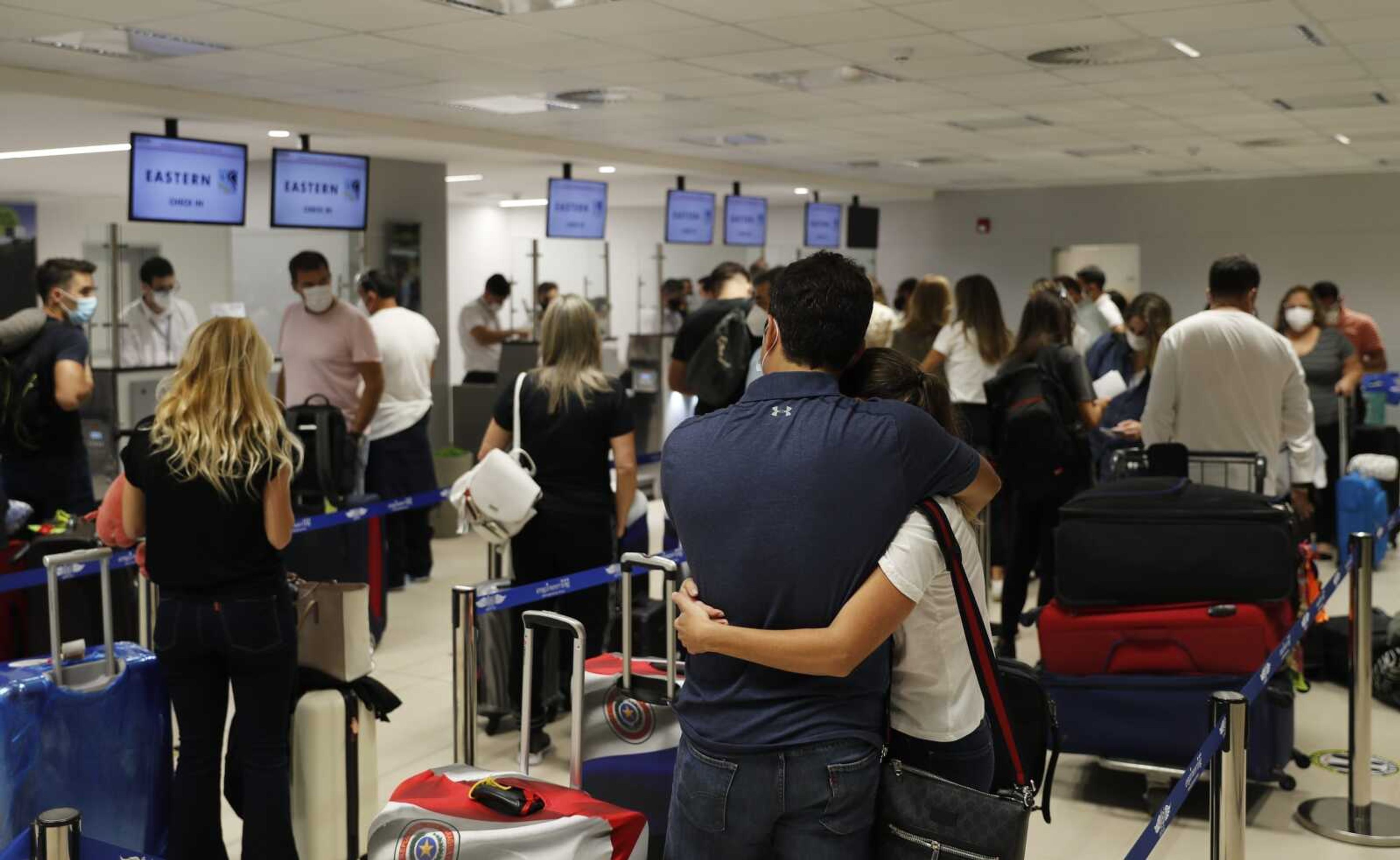 People check in for a flight to Miami on Saturday at Silvio Pettirossi Airport in Luque, Paraguay. Vaccine seekers who can afford to travel are coming to the United States to avoid the long wait, including people who have come from as far as Paraguay.