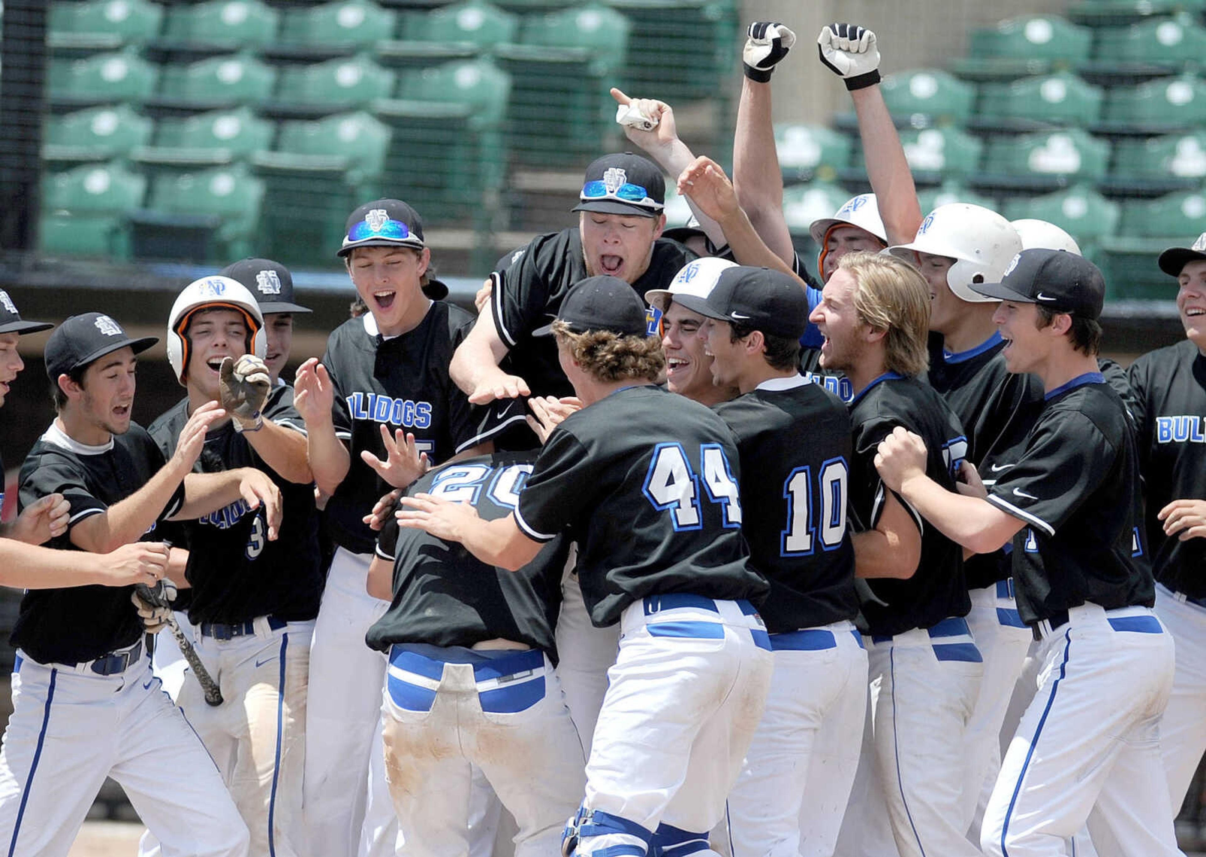 Notre Dame players surround Chase Urhahn as he scores on his grand slam in the sixth inning of the Bulldogs Class 4 semifinal against Smithville, Friday, June 5, 2015, in O'Fallon, Missouri. Notre Dame won 13-3 in six innings. (Laura Simon)