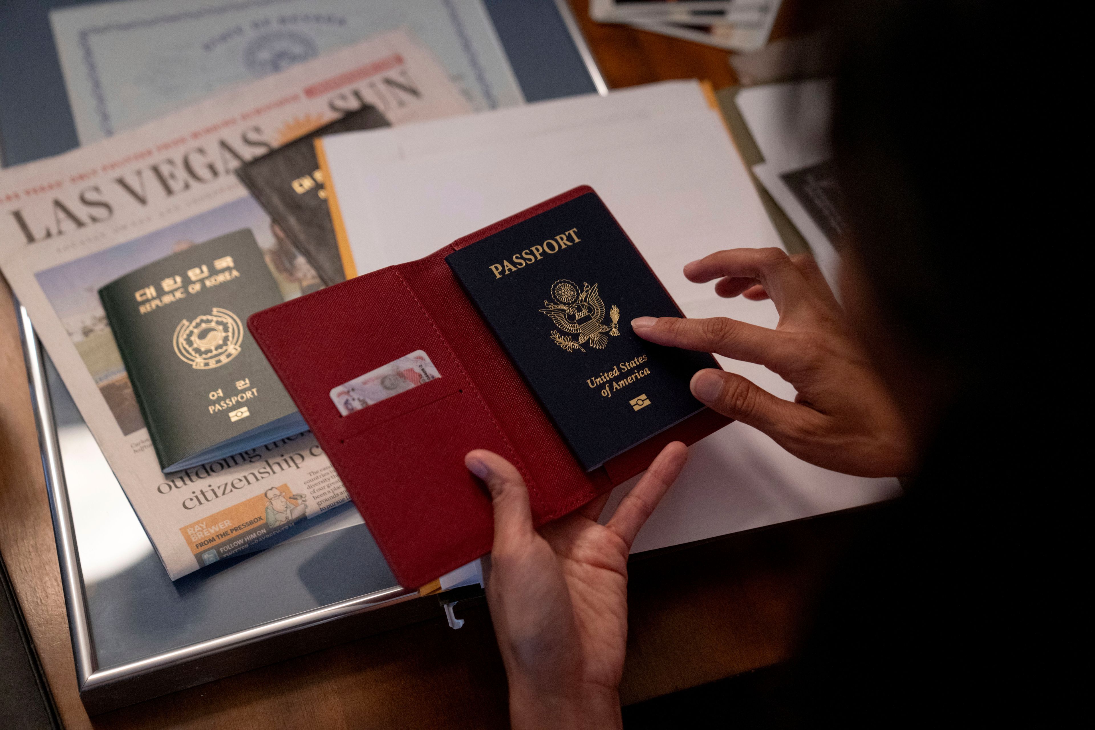 Navy veteran Leah Elmquist holds her U.S. passport in her home, Monday, June 24, 2024, in Las Vegas. She was naturalized in 2022, the day before her 40th birthday and used her new passport for the first time to travel to Paris for the 2024 Summer Olympics. (AP Photo/David Goldman)