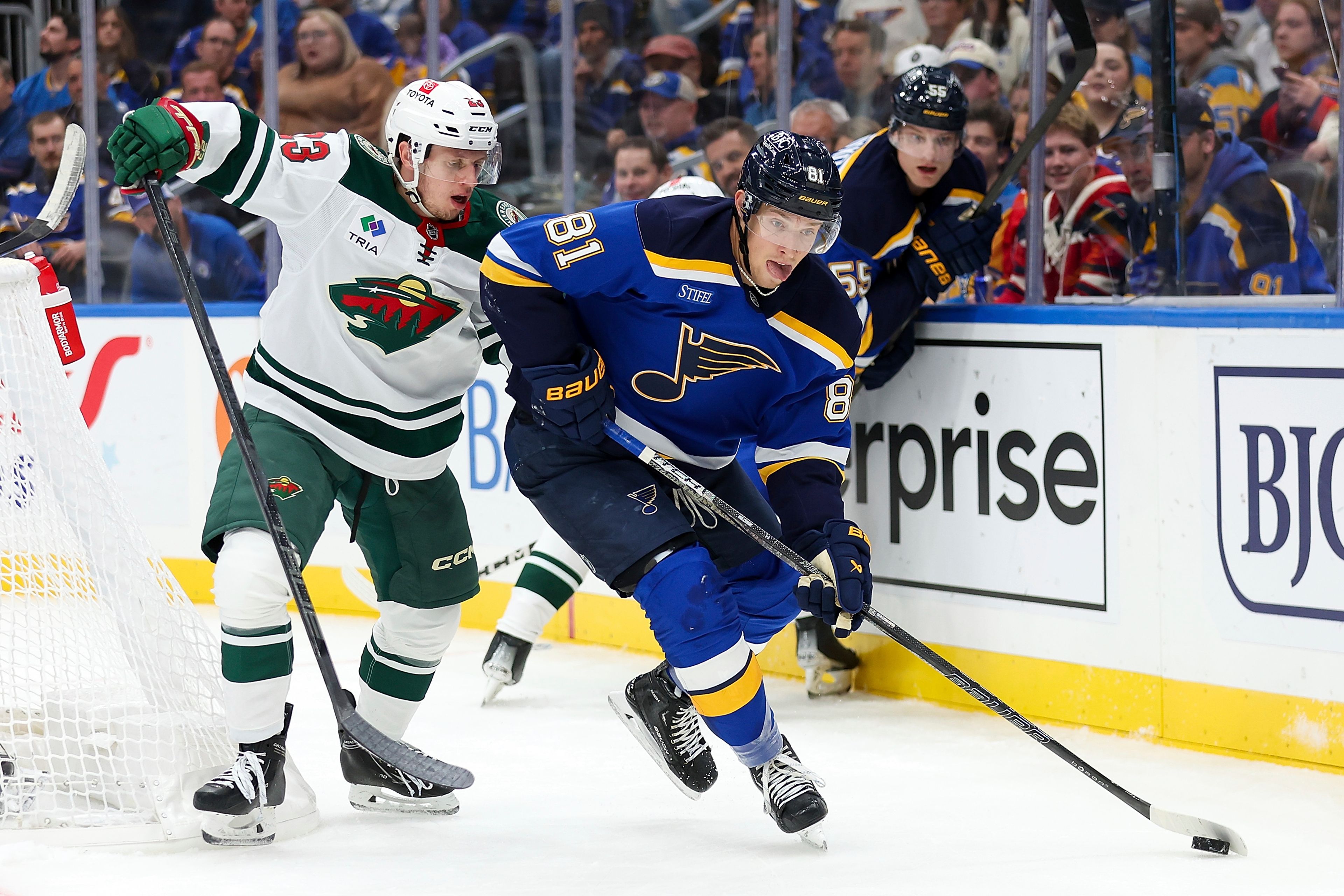 St. Louis Blues' Dylan Holloway (81) controls the puck while under pressure from Minnesota Wild's Marco Rossi (23) during the second period of an NHL hockey game Tuesday, October 15, 2024, in St. Louis. (AP Photo/Scott Kane)