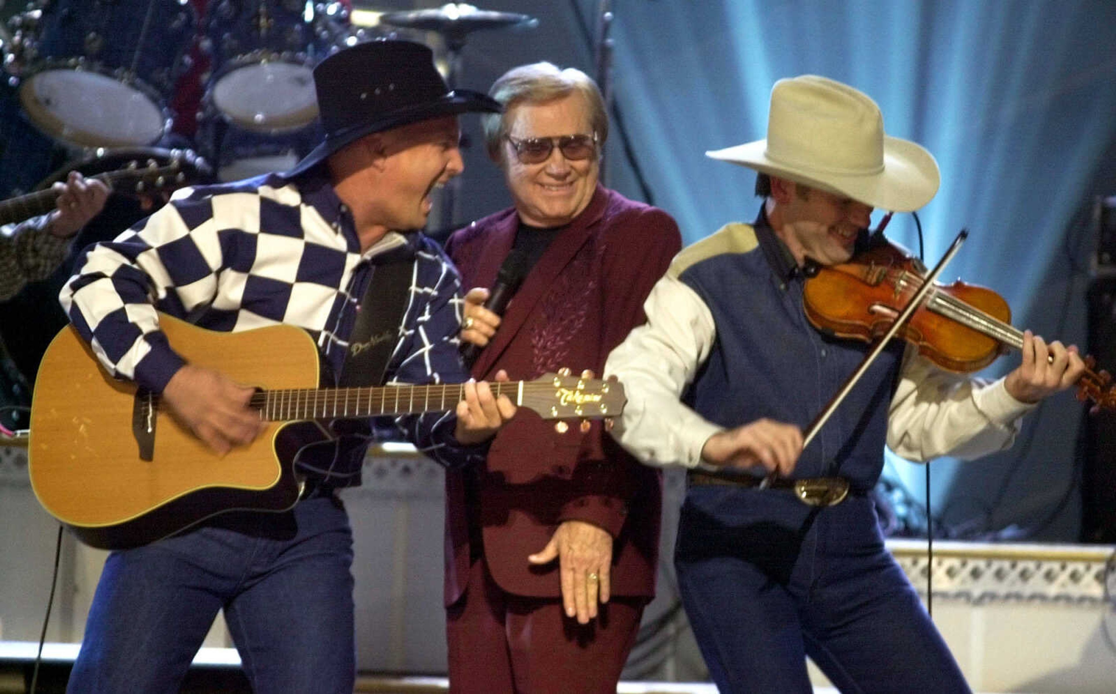 FILE - In this Nov. 7, 2001 file photo, Garth Brooks, left, and George Jones, center, perform their duet "Beer Run" at the Country Music Association Awards show in Nashville, Tenn.   The fiddle player at right is unidentified.   Jones, the peerless, hard-living country singer who recorded dozens of hits about good times and regrets and peaked with the heartbreaking classic "He Stopped Loving Her Today," has died. He was 81. Jones died Friday, April 26, 2013 at Vanderbilt University Medical Center in Nashville after being hospitalized with fever and irregular blood pressure, according to his publicist Kirt Webster.(AP Photo/M. Spencer Green, file)