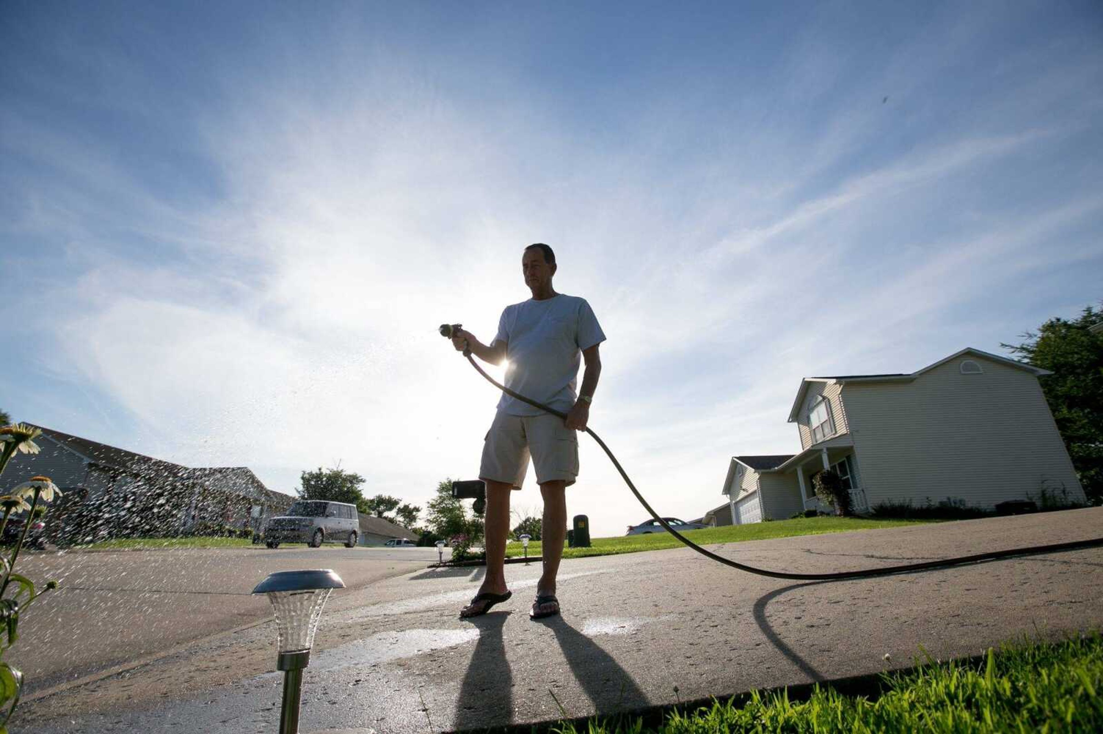 David Lane uses a hose to water a bed of flowers in the front yard of his home Wednesday in the Hillcrest Manor neighborhood in Cape Girardeau.