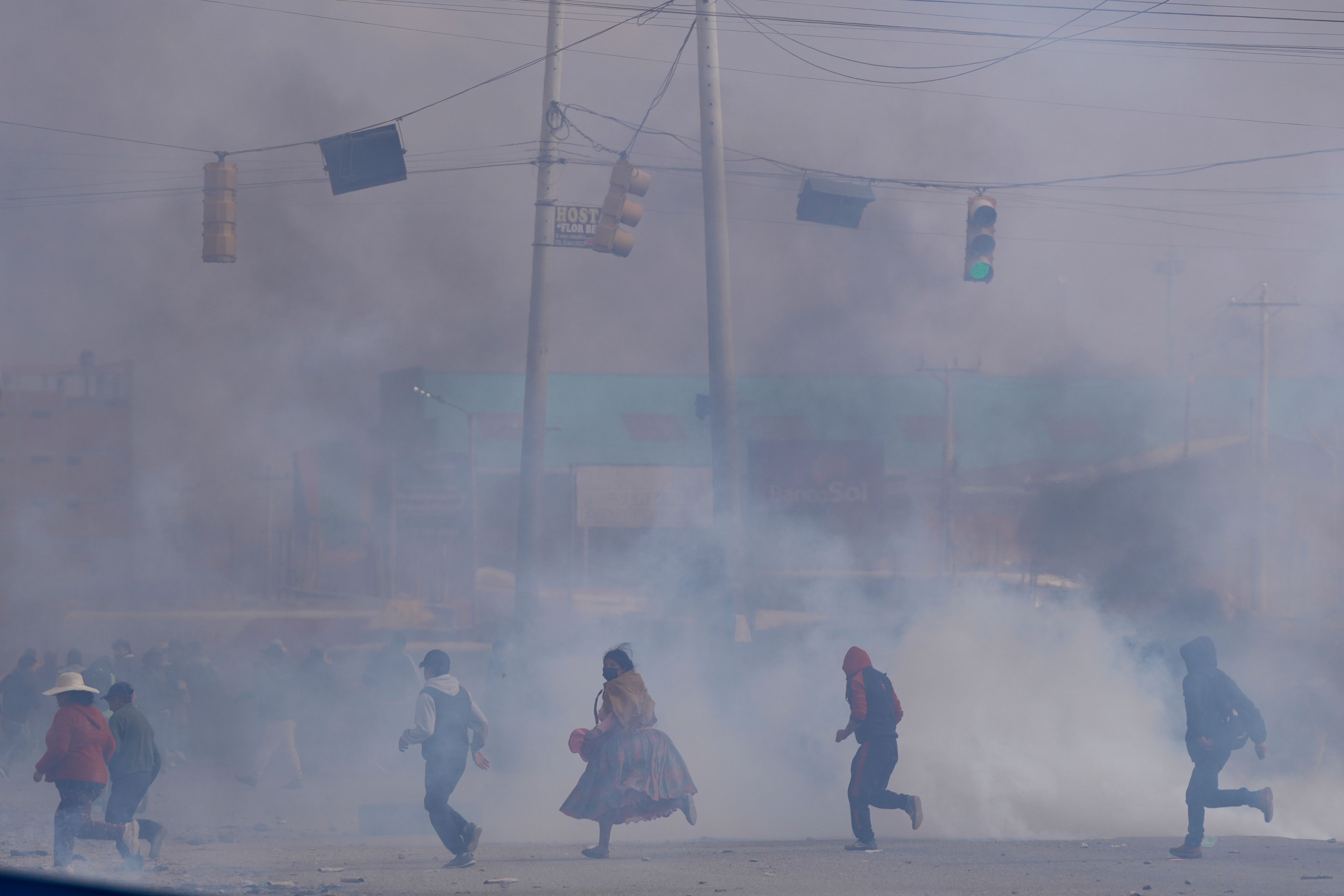 People run through police tear gas during clashes between supporters of both former President Evo Morales and current President Luis Arce in El Alto, Bolivia, Sept. 22, 2024. (AP Photo/Juan Karita)