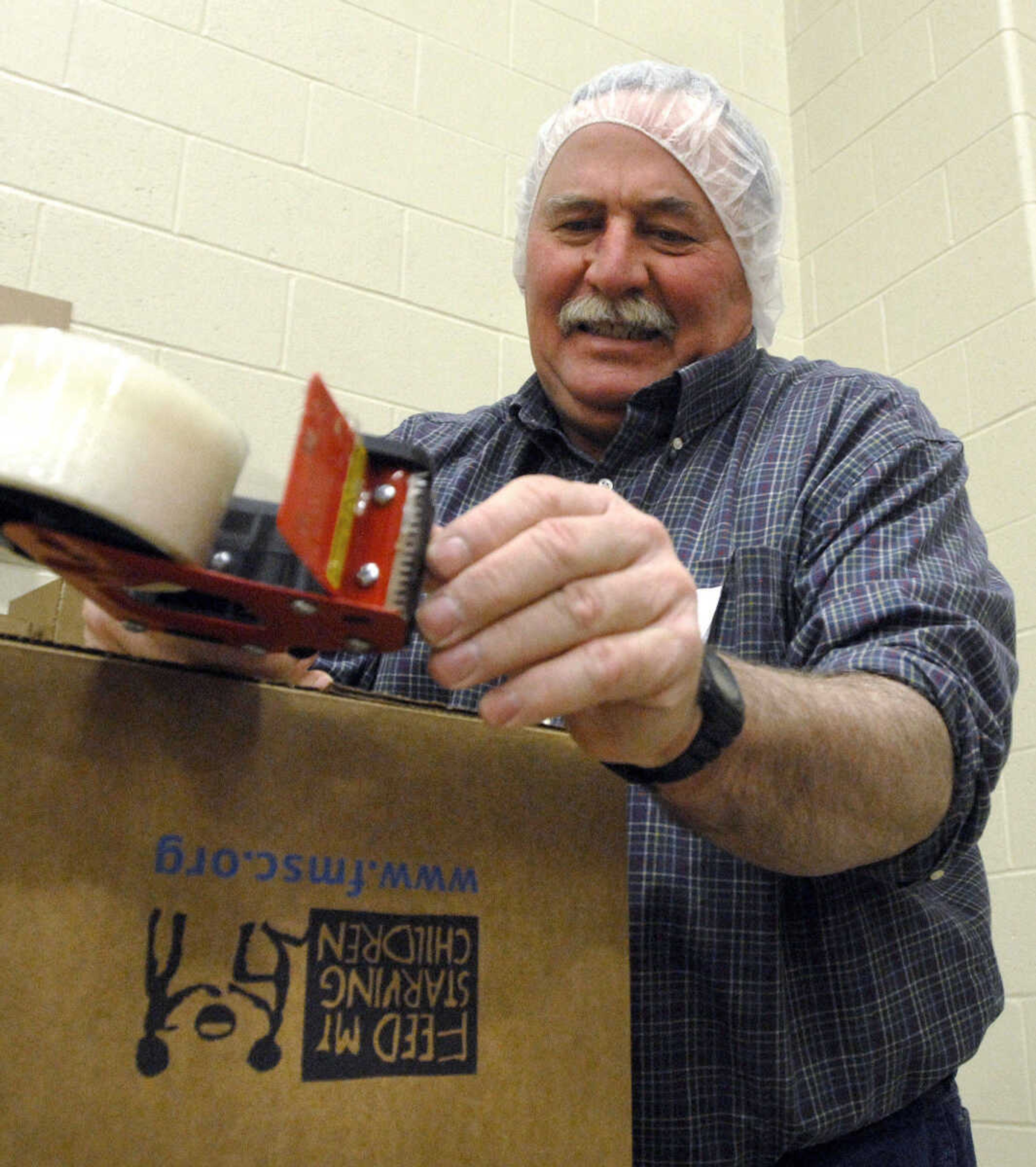 LAURA SIMON ~ lsimon@semissourian.com
Mike Kasten of Millersville, Mo. tries to get advance the packing tape while assembling boxes for the MannaPack  Rice meals Friday night, Dec. 9, 2011 during the Feed My Starving Children Mobilepack event at Shawnee Park center in Cape Girardeau.